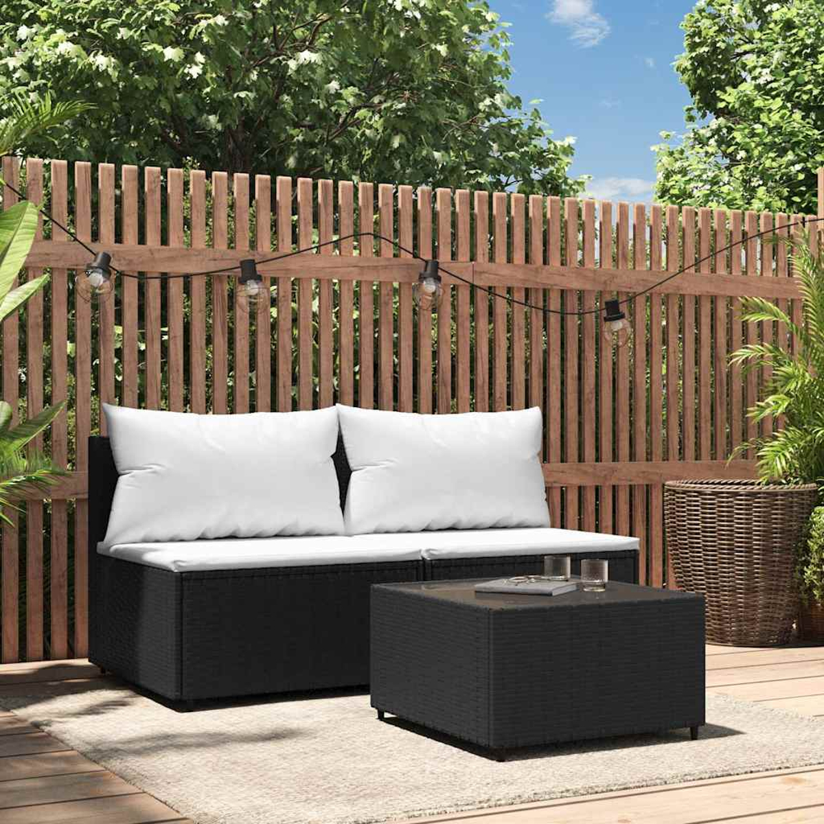 Szene im Freien mit einem schwarzen Korbsitz, weißen Kissen und einem schwarzen quadratischen Couchtisch.