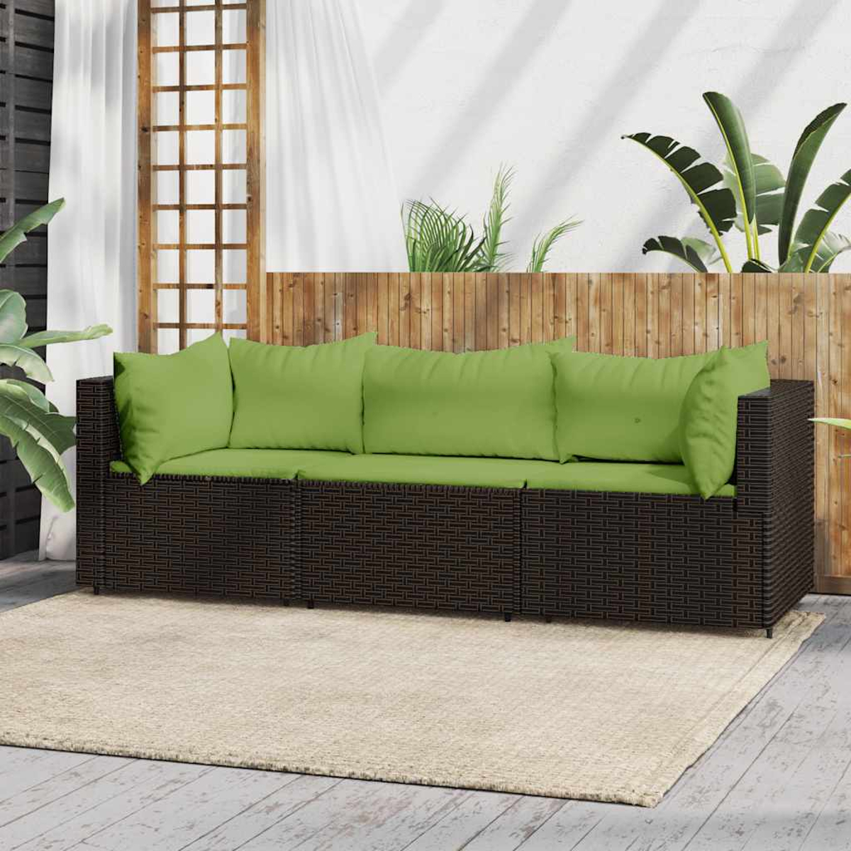 Dunkelbraunes Rattan-Sofa mit grünen Kissen. Draußen, auf einer Terrasse.