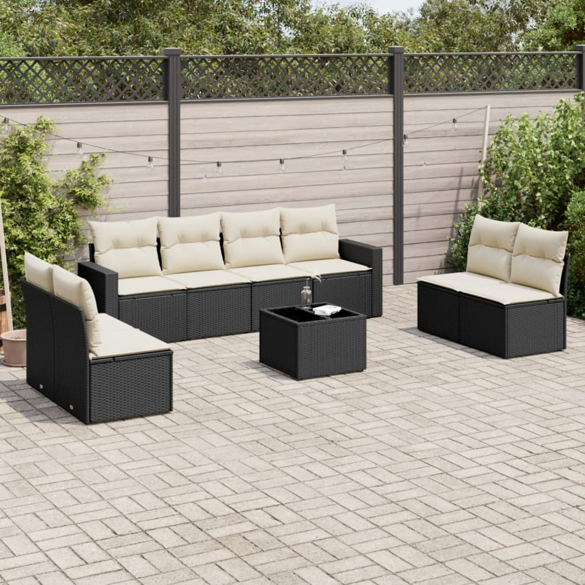 Schwarzes Outdoor-Sofaset aus Korbgeflecht mit cremefarbenen Kissen und einem Couchtisch, auf einer Terrasse.