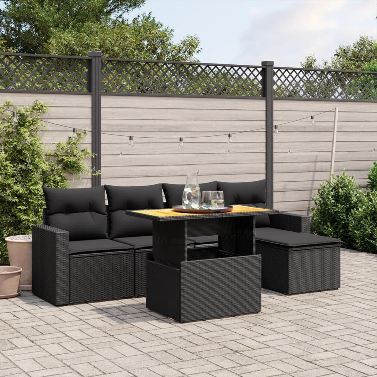 Schwarzes Rattan-Gartenmöbel-Set mit schwarzen Kissen und einem Holztisch.