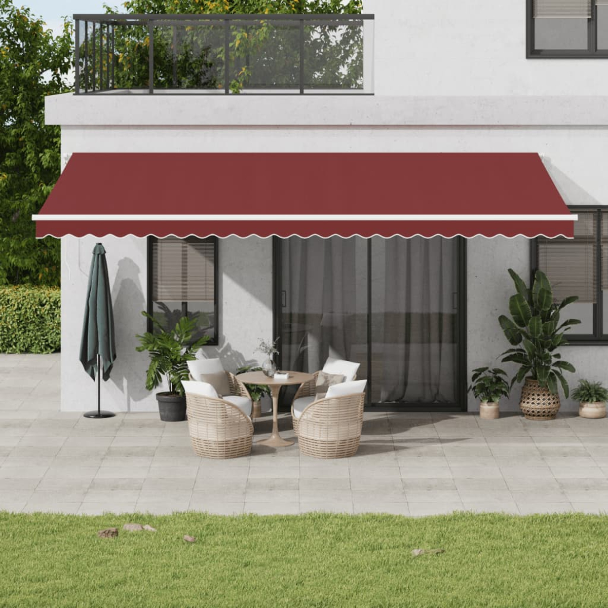 Patio con sedie in rattan, tavolo e tenda da sole rossa.
