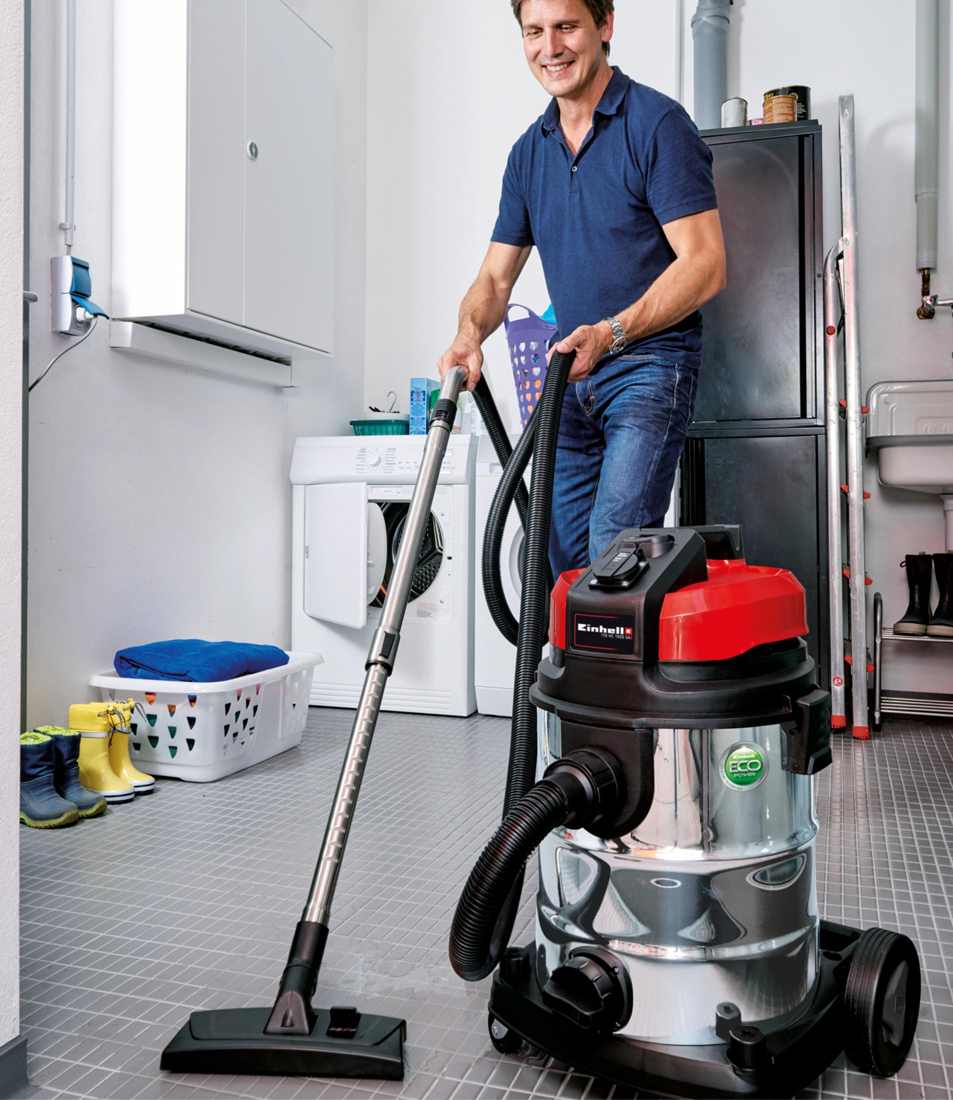 Un hombre aspirando una habitación. Una aspiradora está en uso con varios suministros de limpieza visibles.