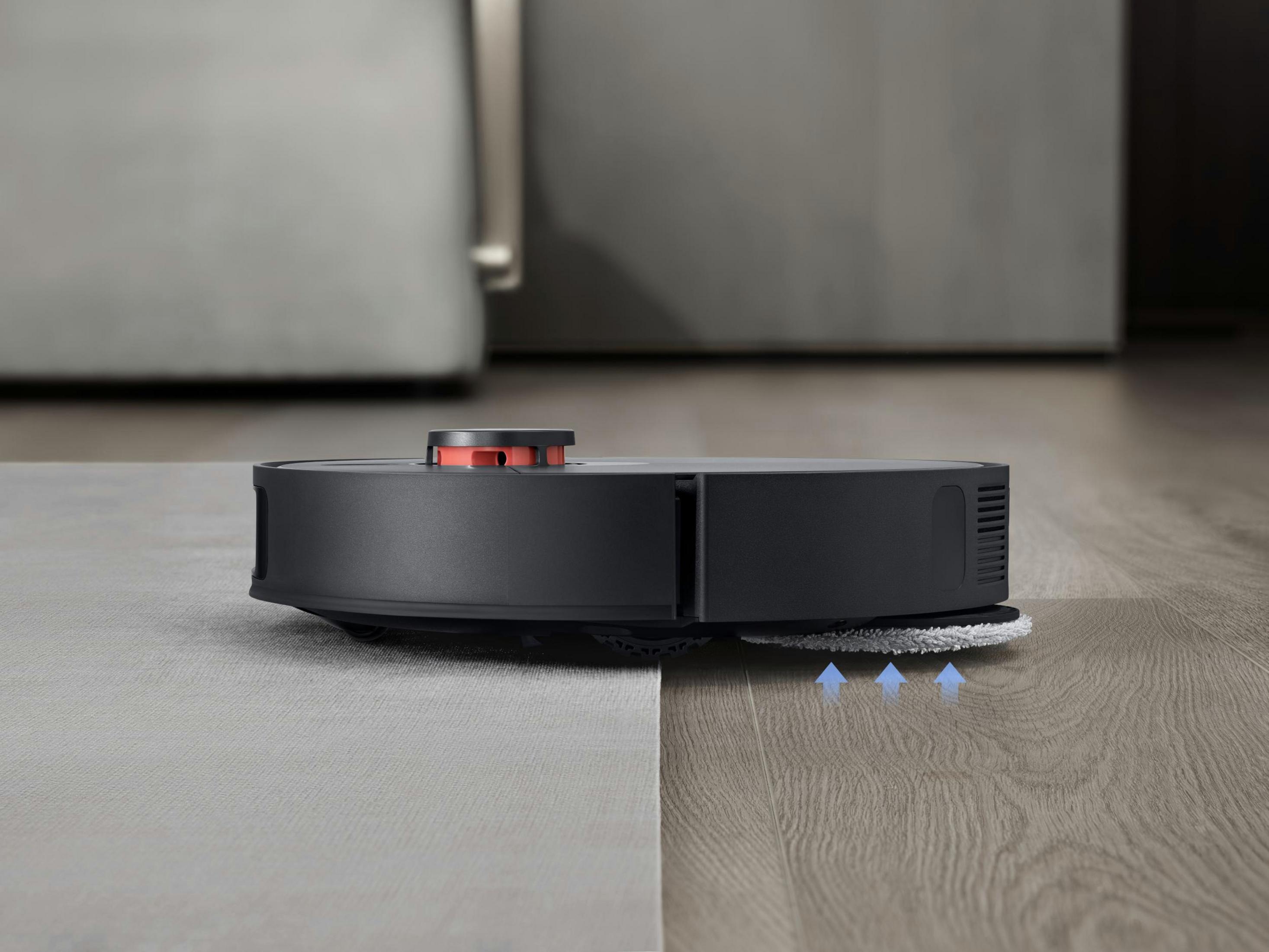 Czarny odkurzacz robot na podłodze, sprzątający w nowoczesnym wnętrzu.