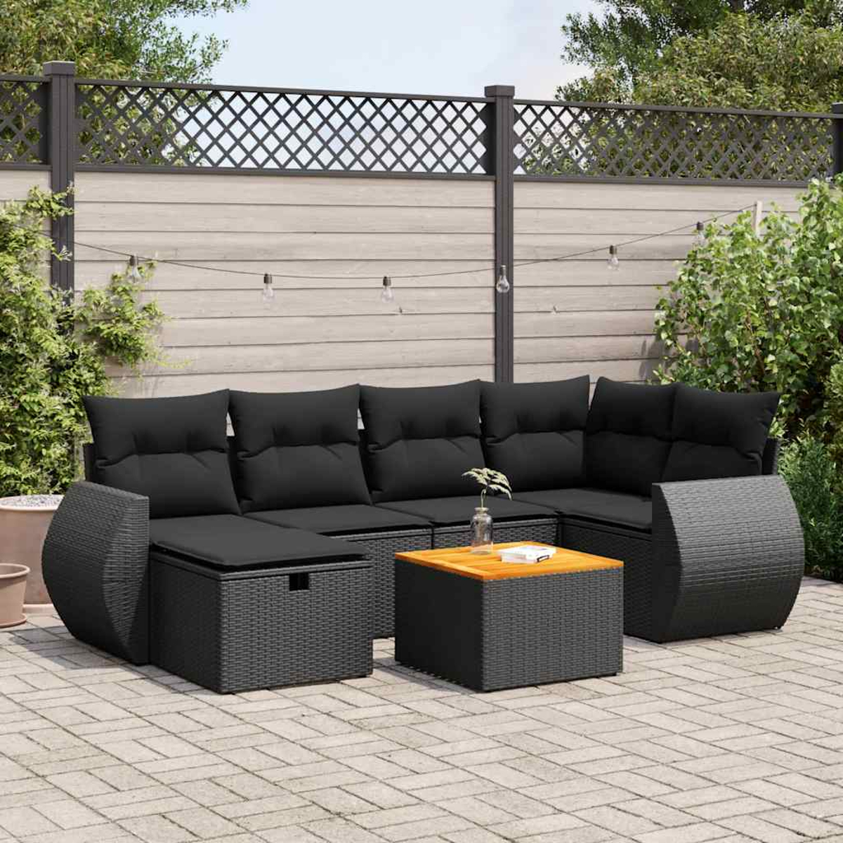 Set divano in vimini nero con cuscini neri e tavolo in legno, su patio pavimentato.