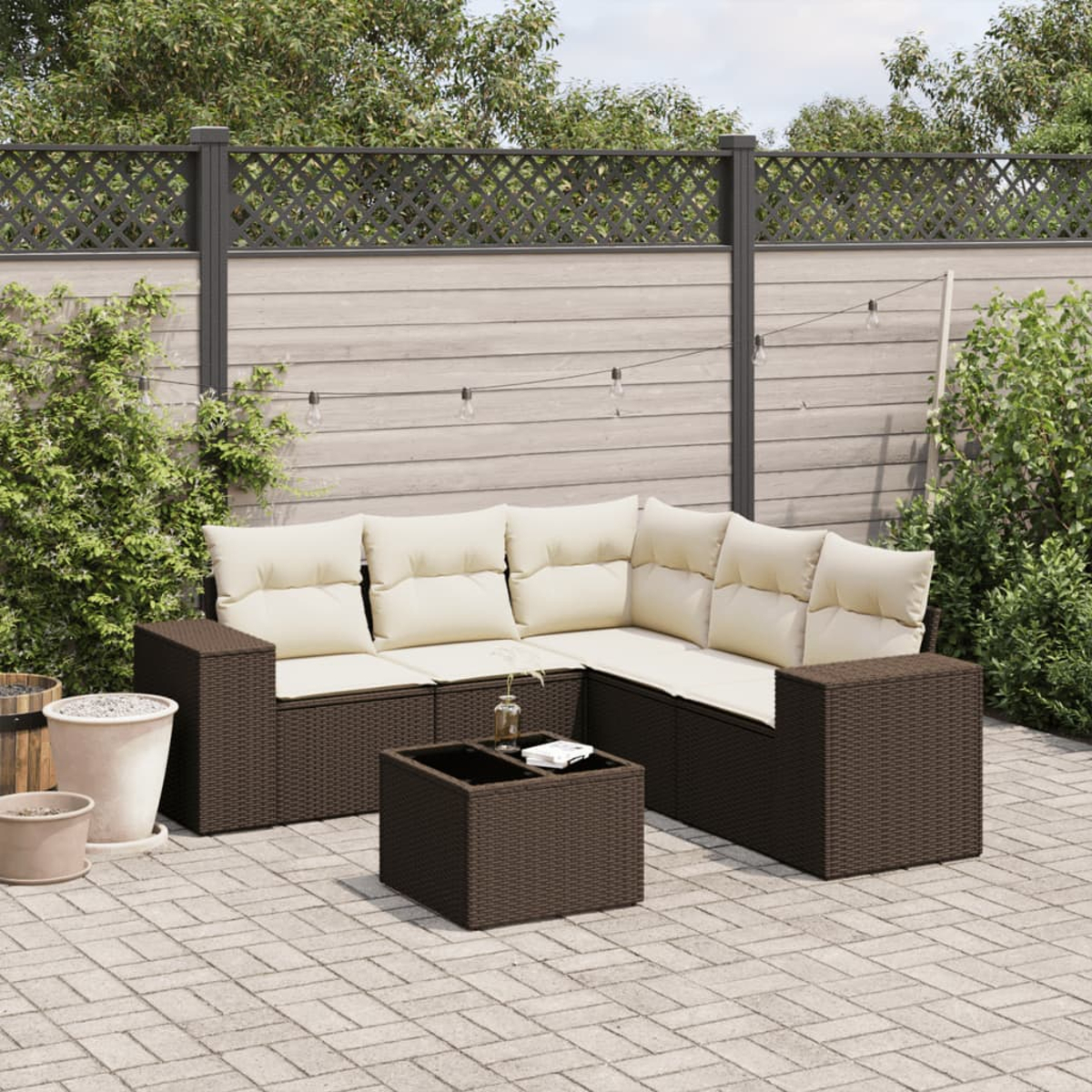Un set di mobili da esterno in vimini marrone con cuscini color crema. Include un divano angolare e un tavolino.