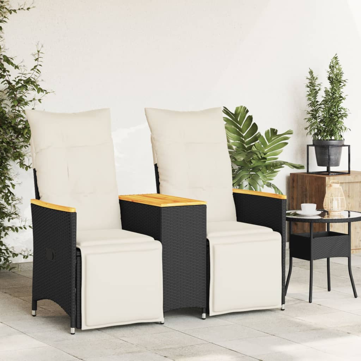 Zwei schwarze Rattan-Stühle mit weißen Kissen und ein Beistelltisch.