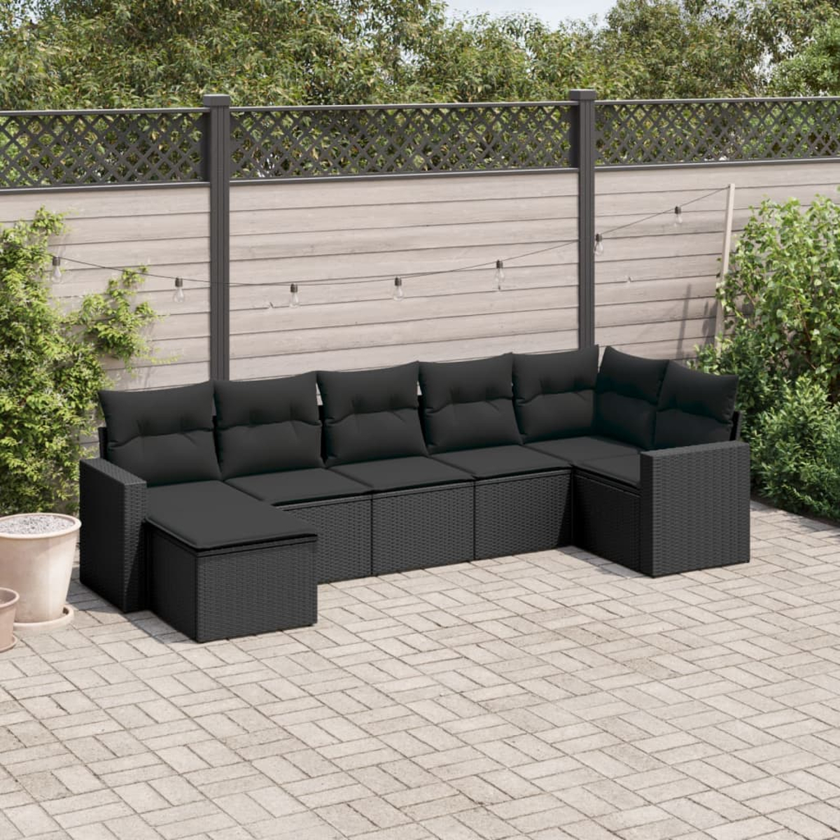 Schwarzes Outdoor-Ecksofa-Set aus Korbgeflecht mit schwarzen Kissen auf einer Terrasse.