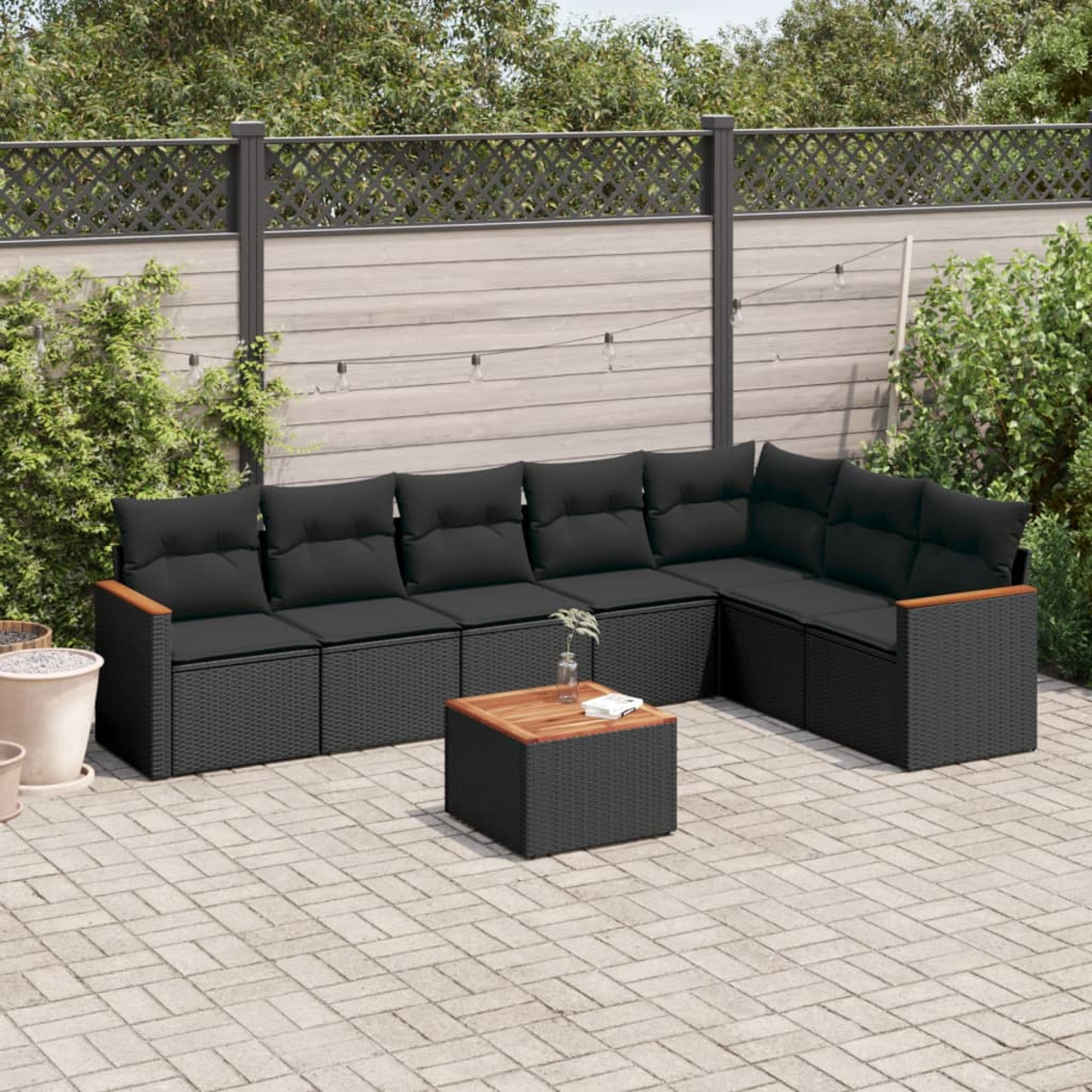 Schwarzes Outdoor-Ecksofa aus Korbgeflecht mit schwarzen Kissen und einem Holztisch.