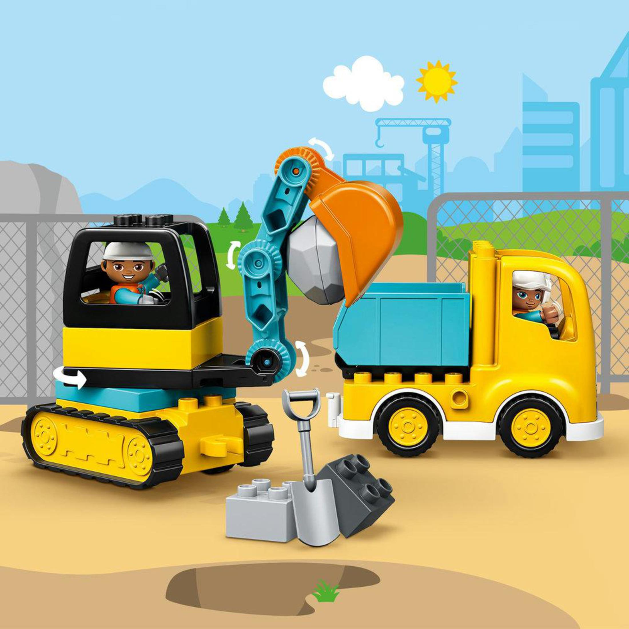 Een Duplo-constructiescène met een graafmachine, vrachtwagen en twee figuren. De scène speelt zich af in een bouwzone.