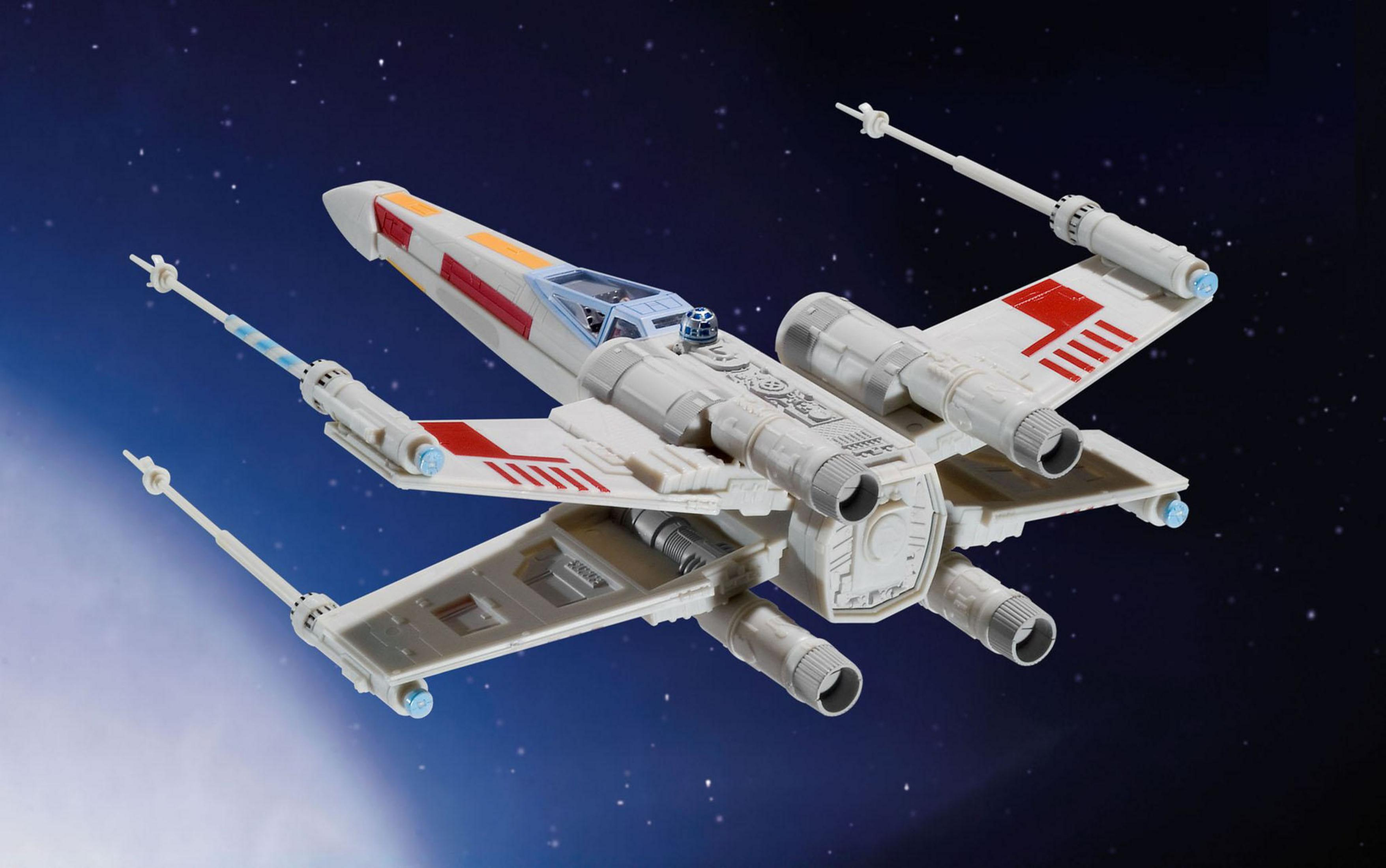 Star Wars X-wing jager in vlucht tegen een sterrenachtergrond. Gedetailleerd model met rode en witte markeringen.