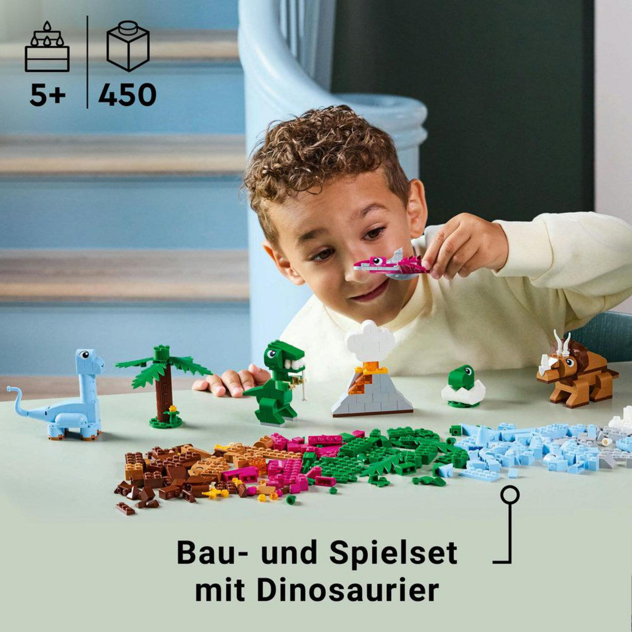 Chłopiec bawiący się modelami dinozaurów LEGO i klockami na stole z innymi figurkami.