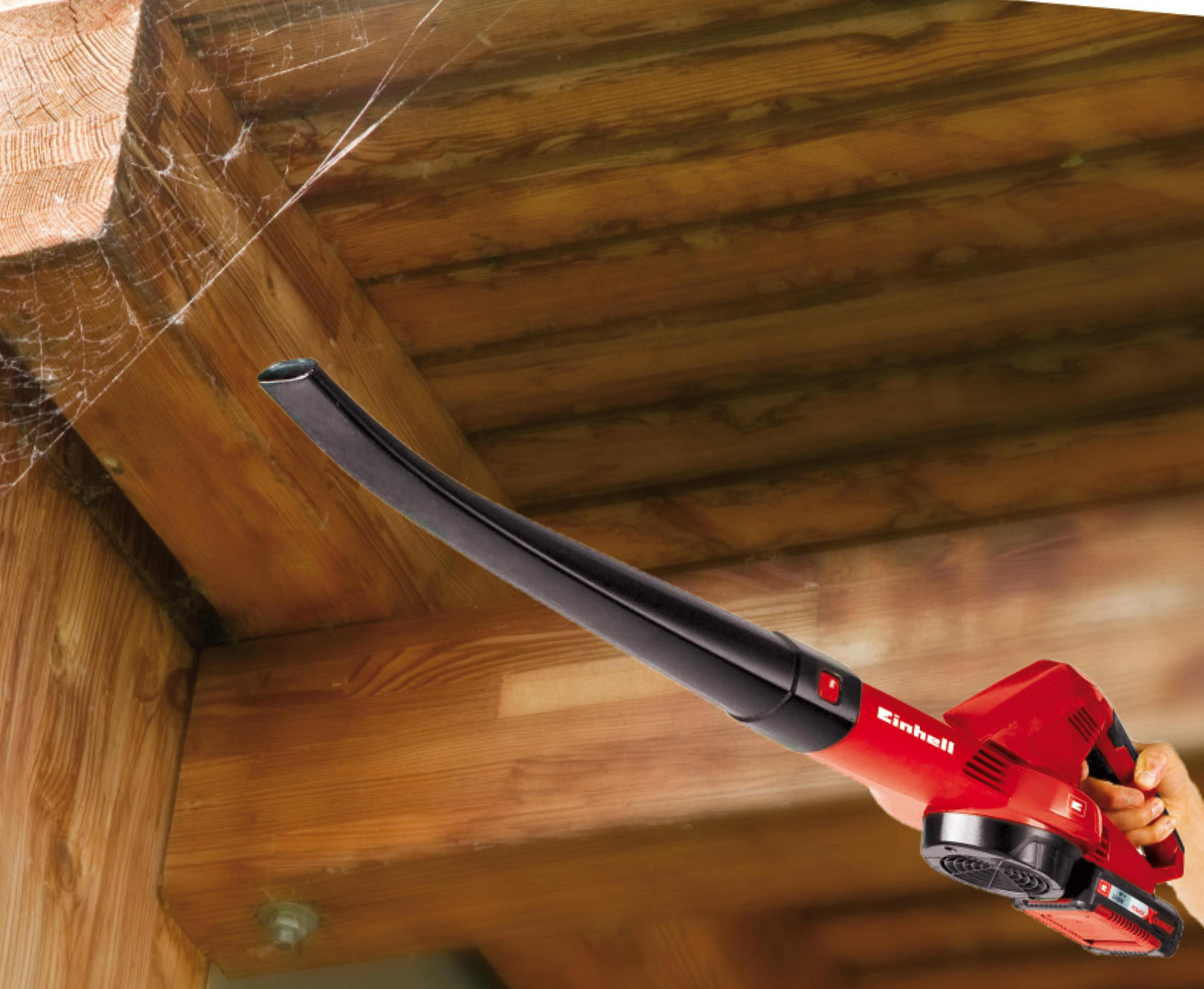 Czerwona dmuchawa do liści w użyciu, dmuchająca na drewniane belki.