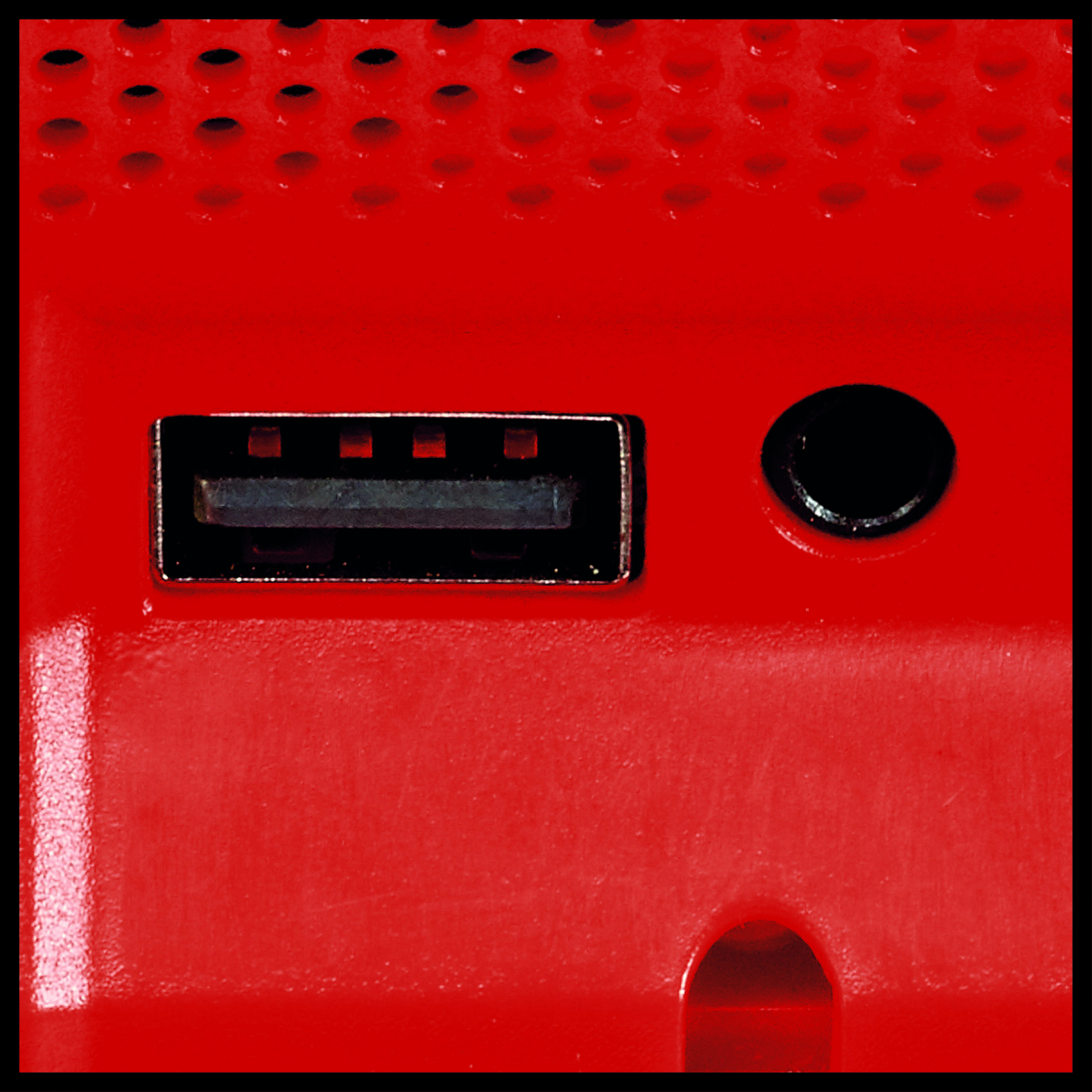 Un primo piano di un dispositivo rosso con una porta USB e un foro, forse per l'audio.