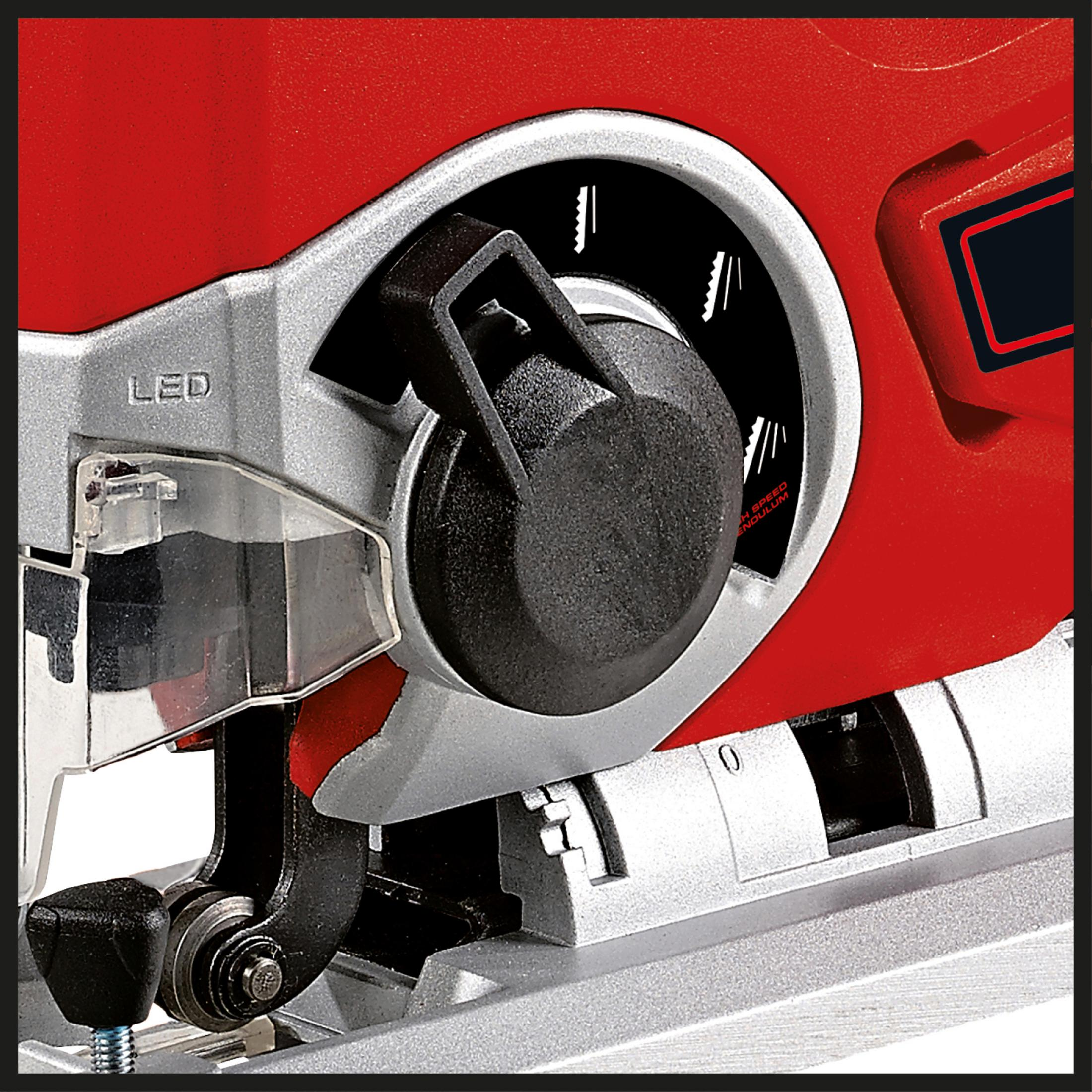 Zbliżenie czerwono-srebrnej wyrzynarki pokazujące mechanizm mocowania brzeszczotu i czarne pokrętło.