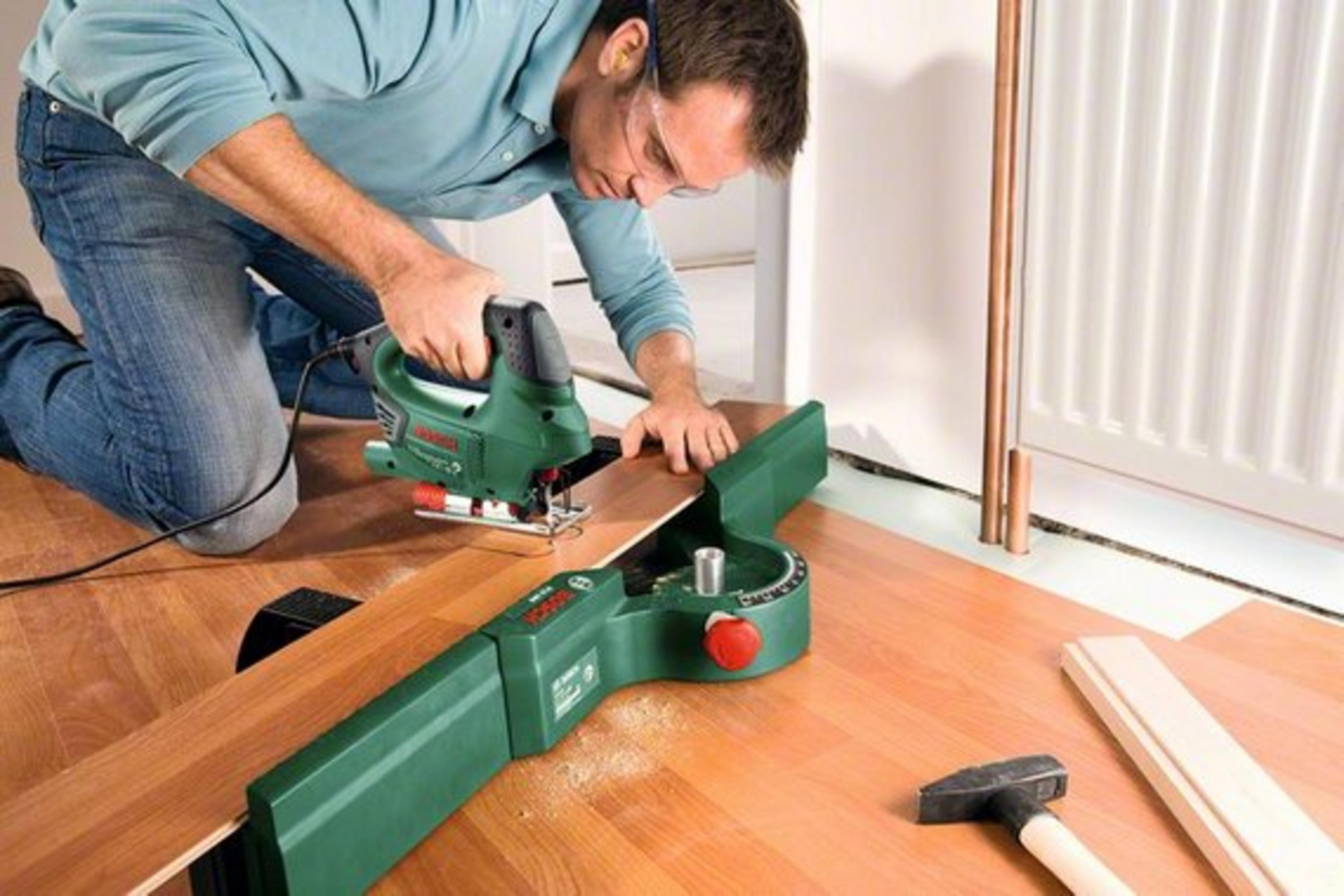 Mężczyzna używający wyrzynarki na drewnianej desce.