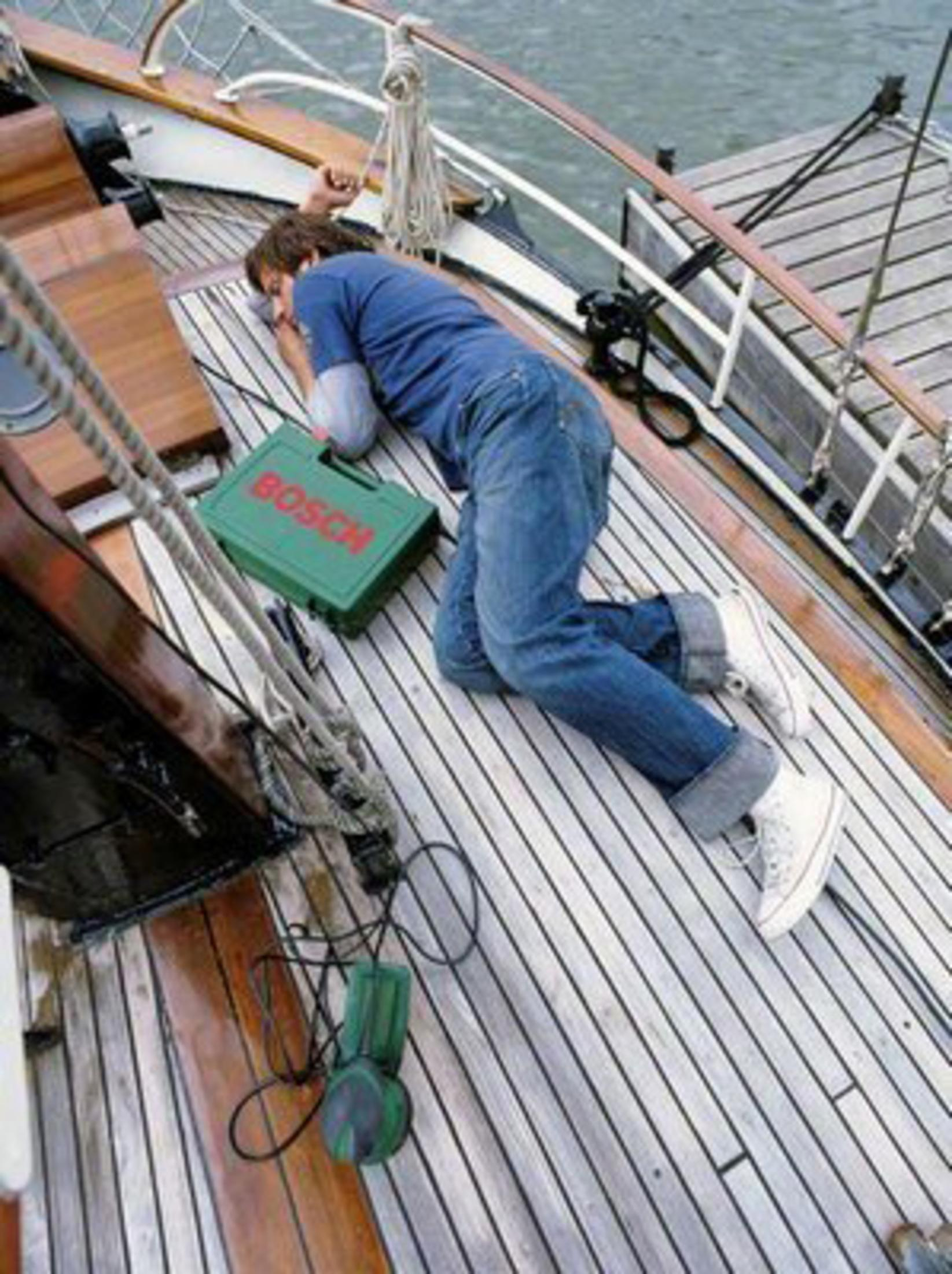 Mann liegt auf Bootsdeck neben grüner Bosch Werkzeugkiste und Stichsäge.