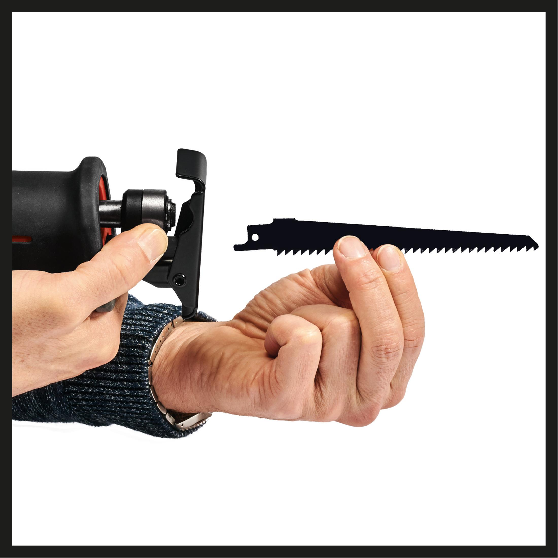 Ręka trzyma czarne ostrze obok piły elektrycznej na białym tle.