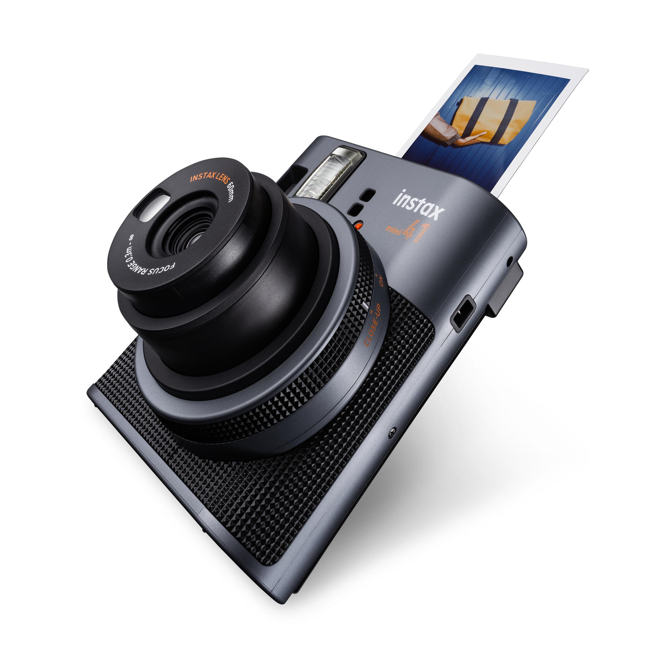 Eine schwarze Kamera, bei der ein Foto gedruckt wird. Das Objektiv ist groß und die Kamera hat ein orangefarbenes Design.