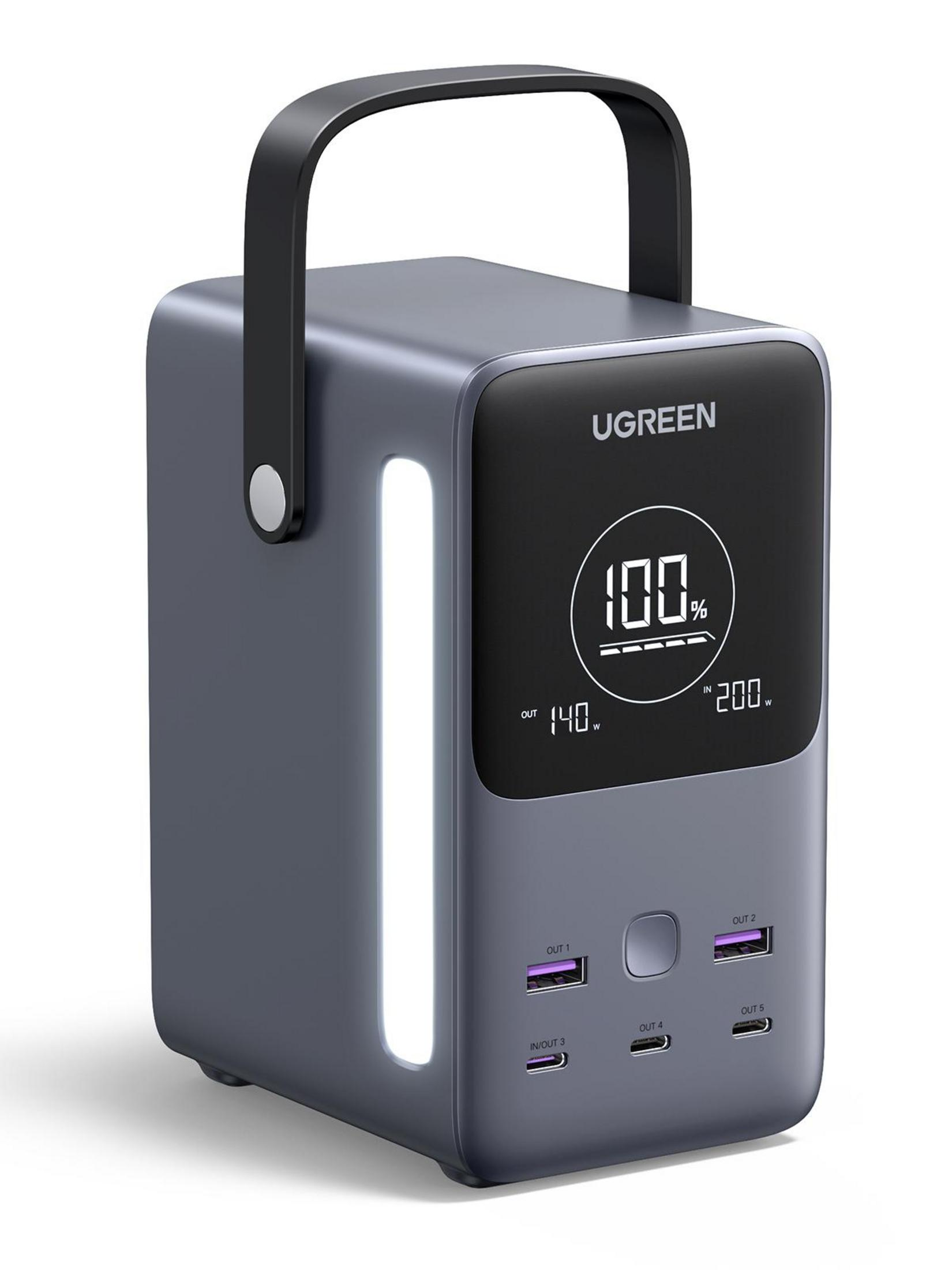 Ciemnoszary przenośny power bank z uchwytem i ekranem pokazującym 100% naładowania. Widoczne kilka portów.