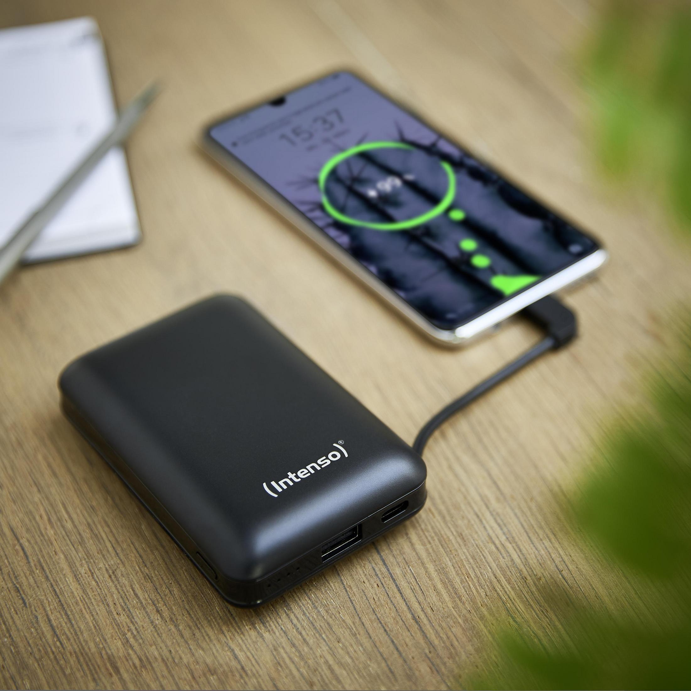 Batería externa negra cargando un teléfono. Teléfono muestra icono de carga.