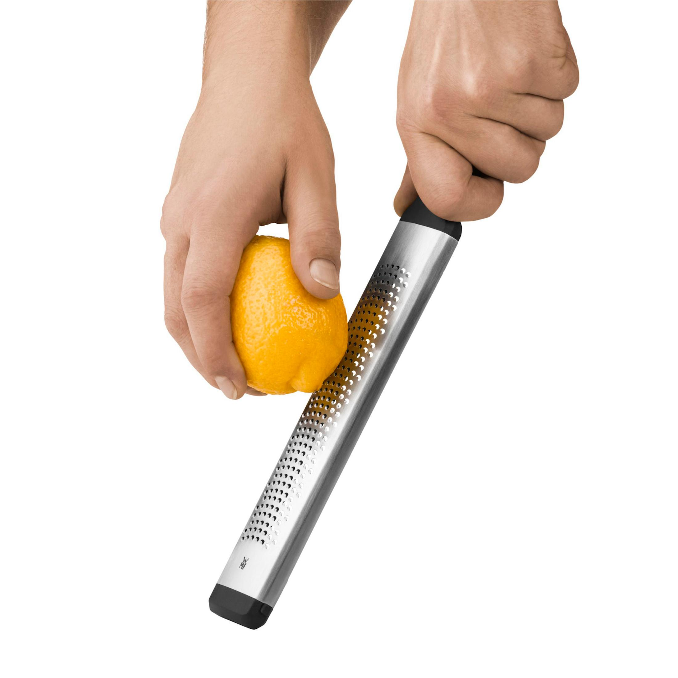 Bir kişi, gümüş bir rende ile limon rendeleyerek. Sarı limon, beyaz zemin.