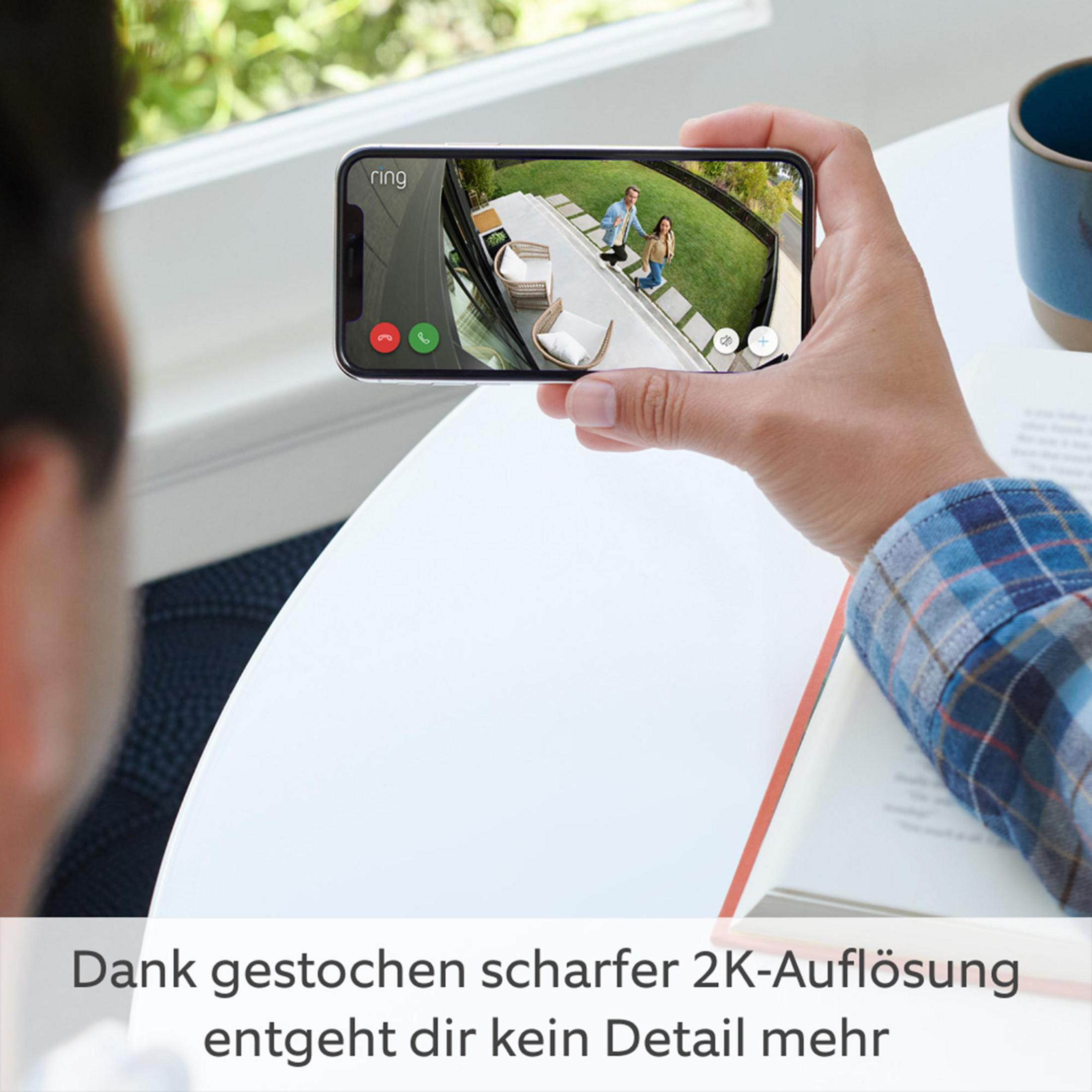 Osoba trzymająca smartfon wyświetlający transmisję wideo na żywo z ludźmi na trawniku.