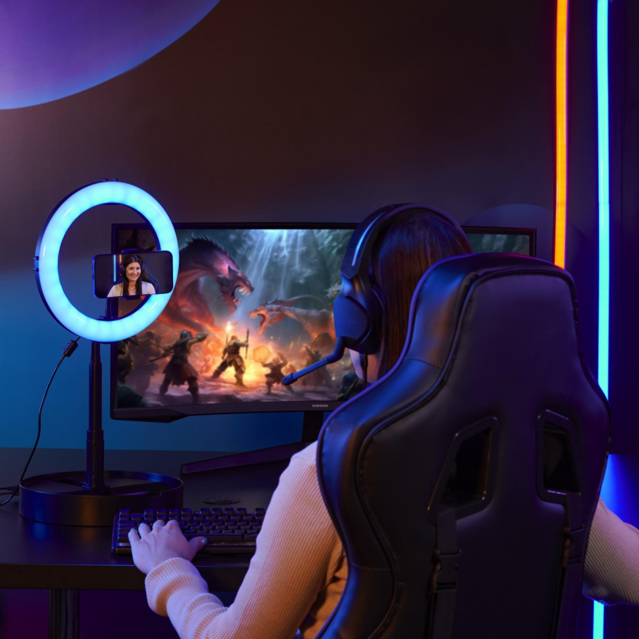 Osoba grająca z oświetleniem pierścieniowym i monitorem pokazującym grę. Kobieta na oświetleniu pierścieniowym. Czarny stół.