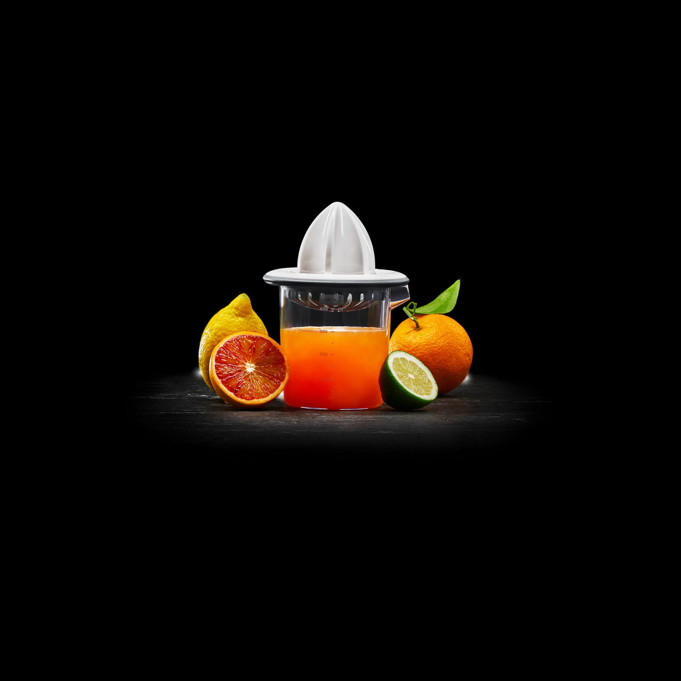 Entsafter mit Orangensaft. Aufgeschnittene Orange, Zitrone und Limette auf schwarzem Grund.