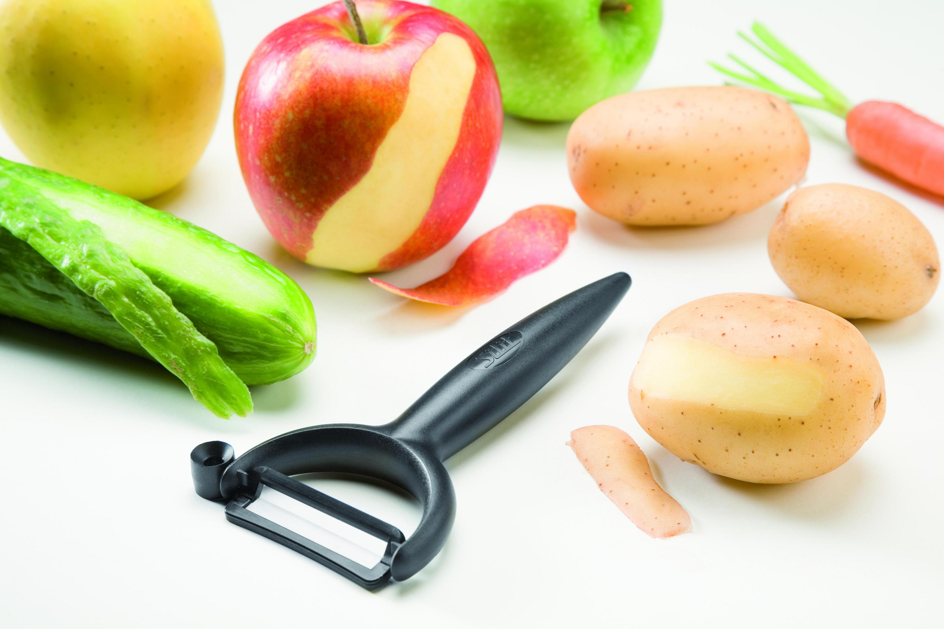 Schwarzer Schäler mit verschiedenen Früchten und Gemüse wie Äpfeln, Kartoffeln, Karotten.
