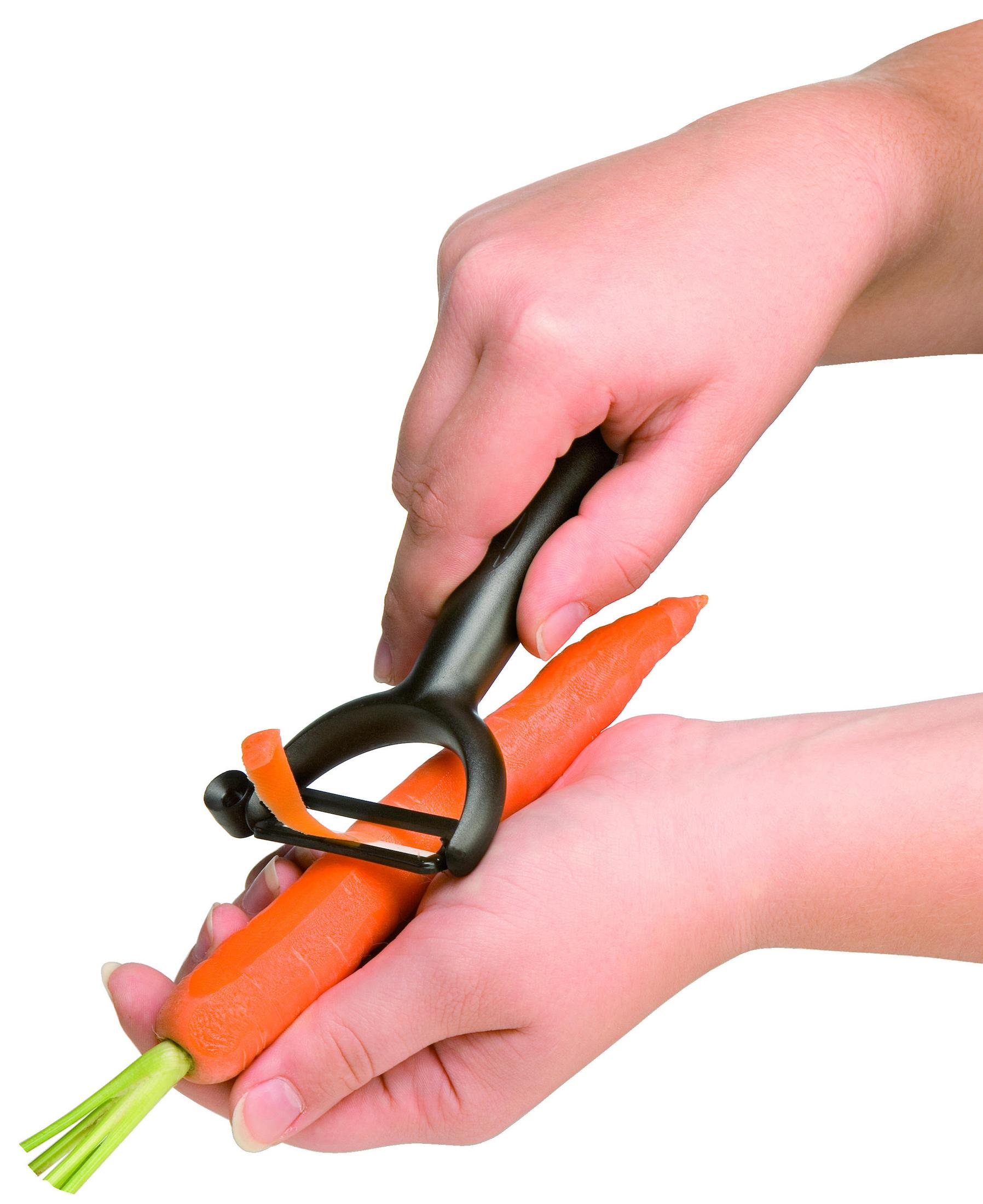 Hände schälen eine Karotte mit einem schwarzen Schäler. Die Karotte ist orange.