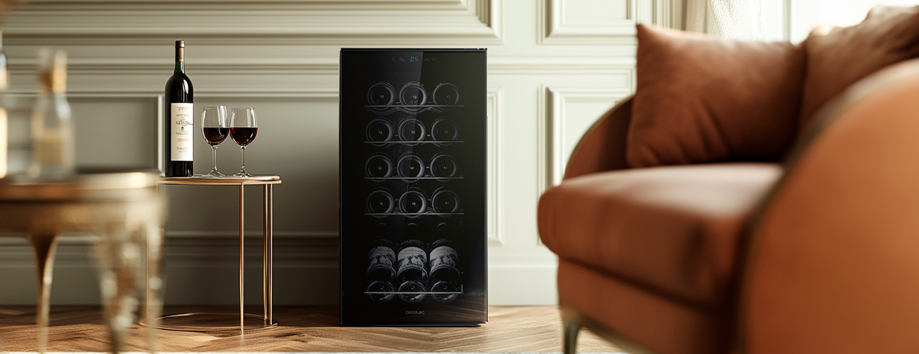 Chłodziarka do wina z butelkami, kieliszkami i sofą.