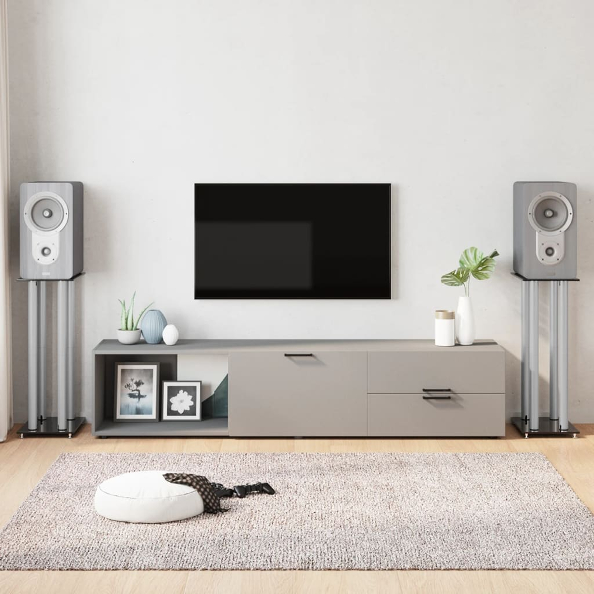 Wohnzimmer-Setup mit Fernseher, Lautsprechern, einem Teppich und einem Konsolentisch mit Dekoration.
