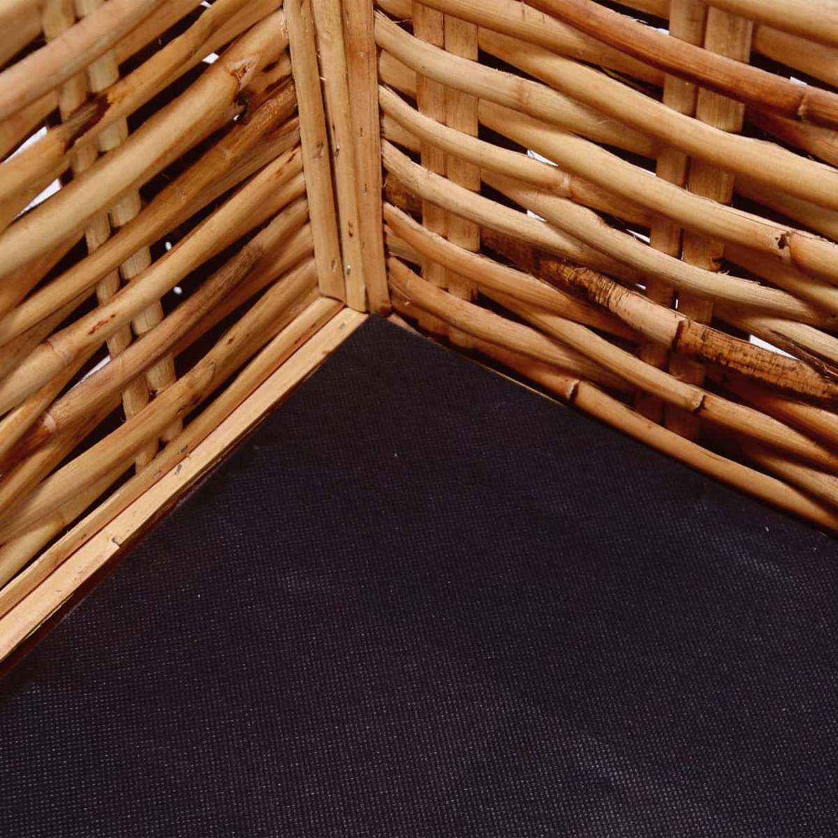 Weidenkorb-Ecke: gewebtes braunes Material, schwarzer Stoff am Boden. Nahaufnahme einer Ecke.
