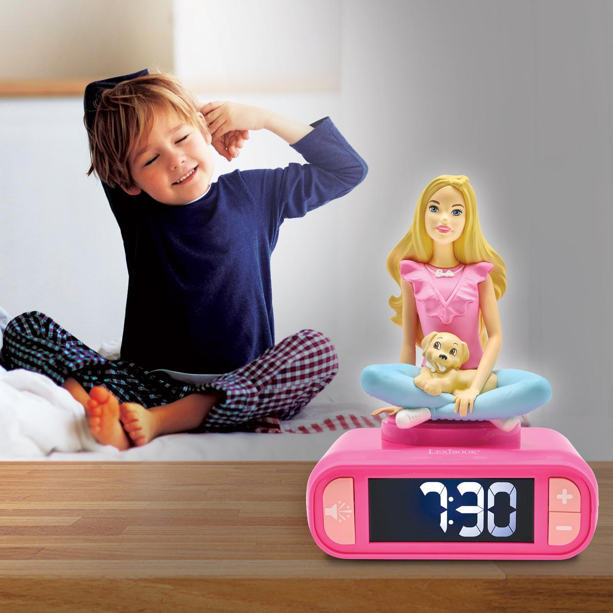 Un niño se estira cerca de un despertador Barbie. El reloj muestra 7:30. Figura Barbie y cachorro en él.