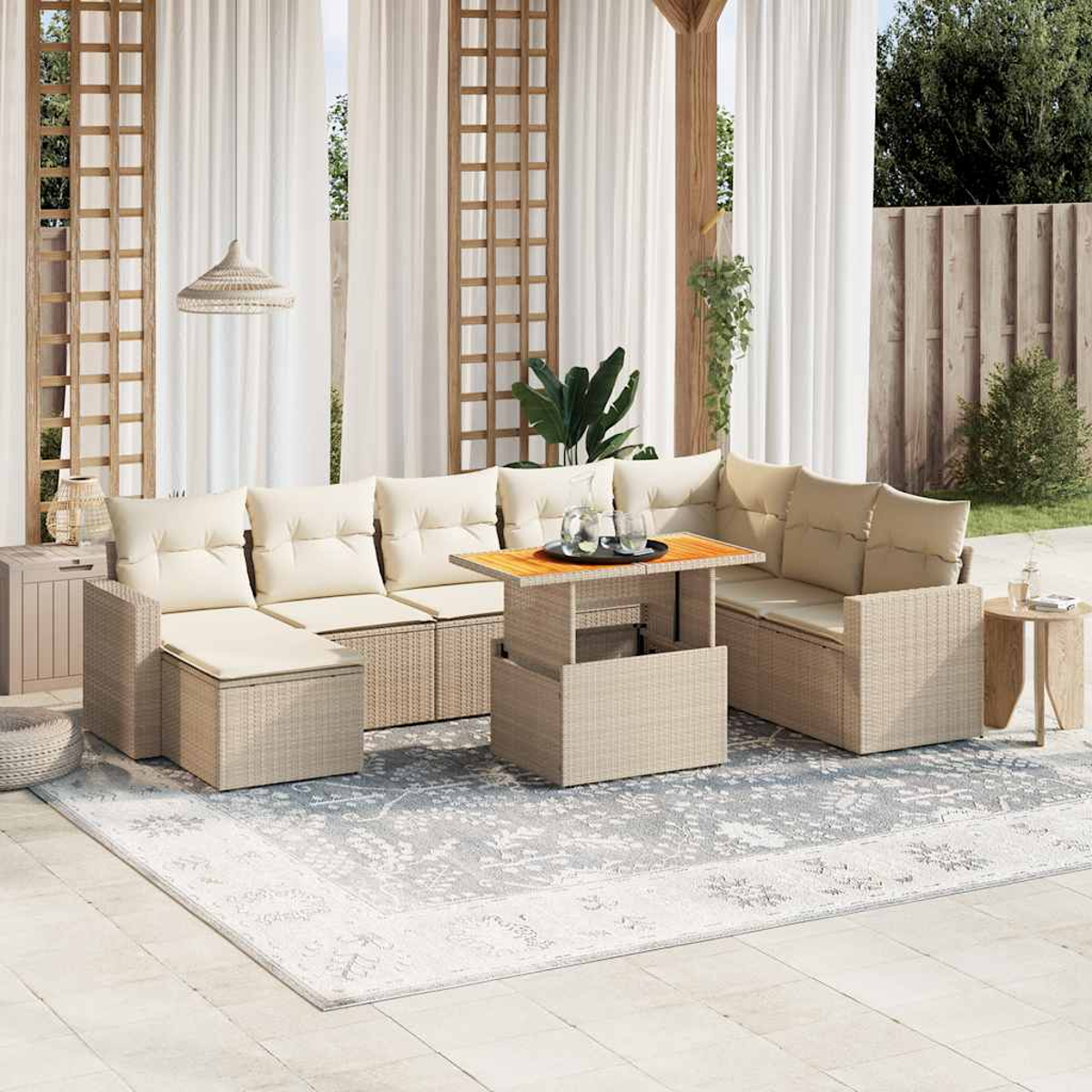 Un divano componibile beige per esterni con un tavolino in legno e un tappeto. Tende e piante sullo sfondo.