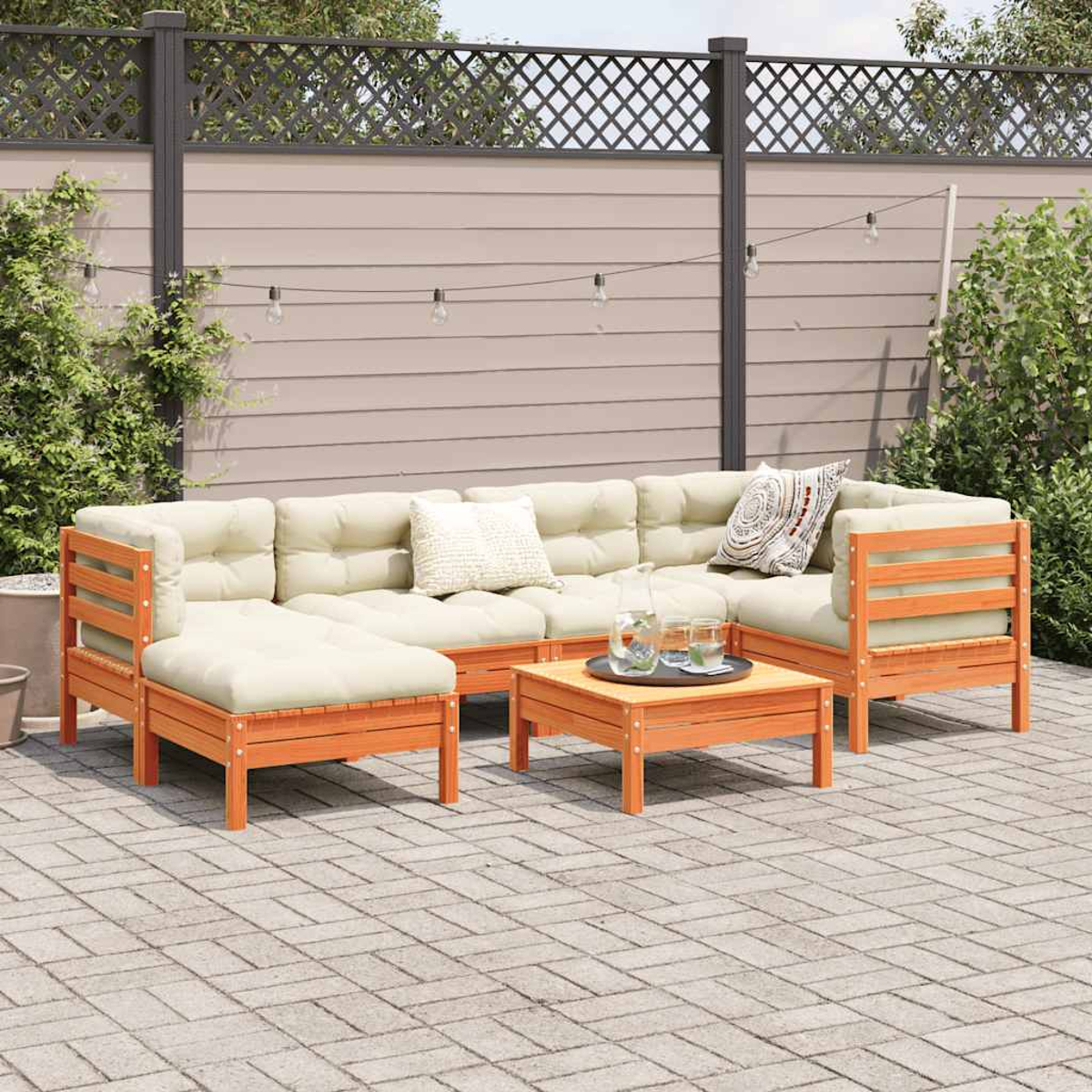 Outdoor-Holz-Terrassenmöbel mit Sofa, Kissen und Tisch. Im Hintergrund ein Zaun.