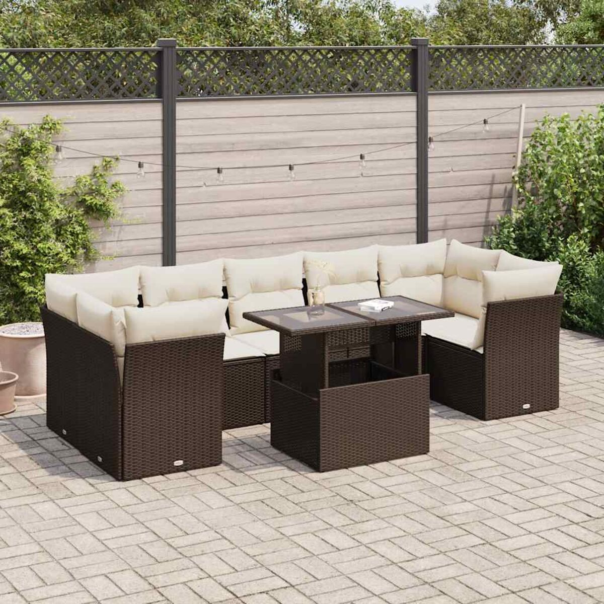 Divano componibile da esterno in rattan marrone con cuscini chiari e un tavolino sollevabile su un patio.