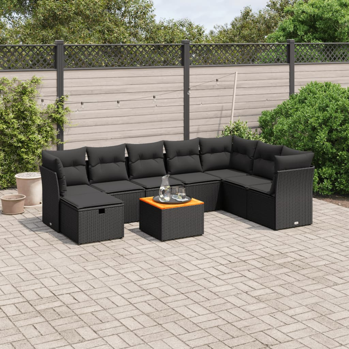Gartensofa mit schwarzen Kissen, einem Couchtisch, auf einer Steinterrasse.