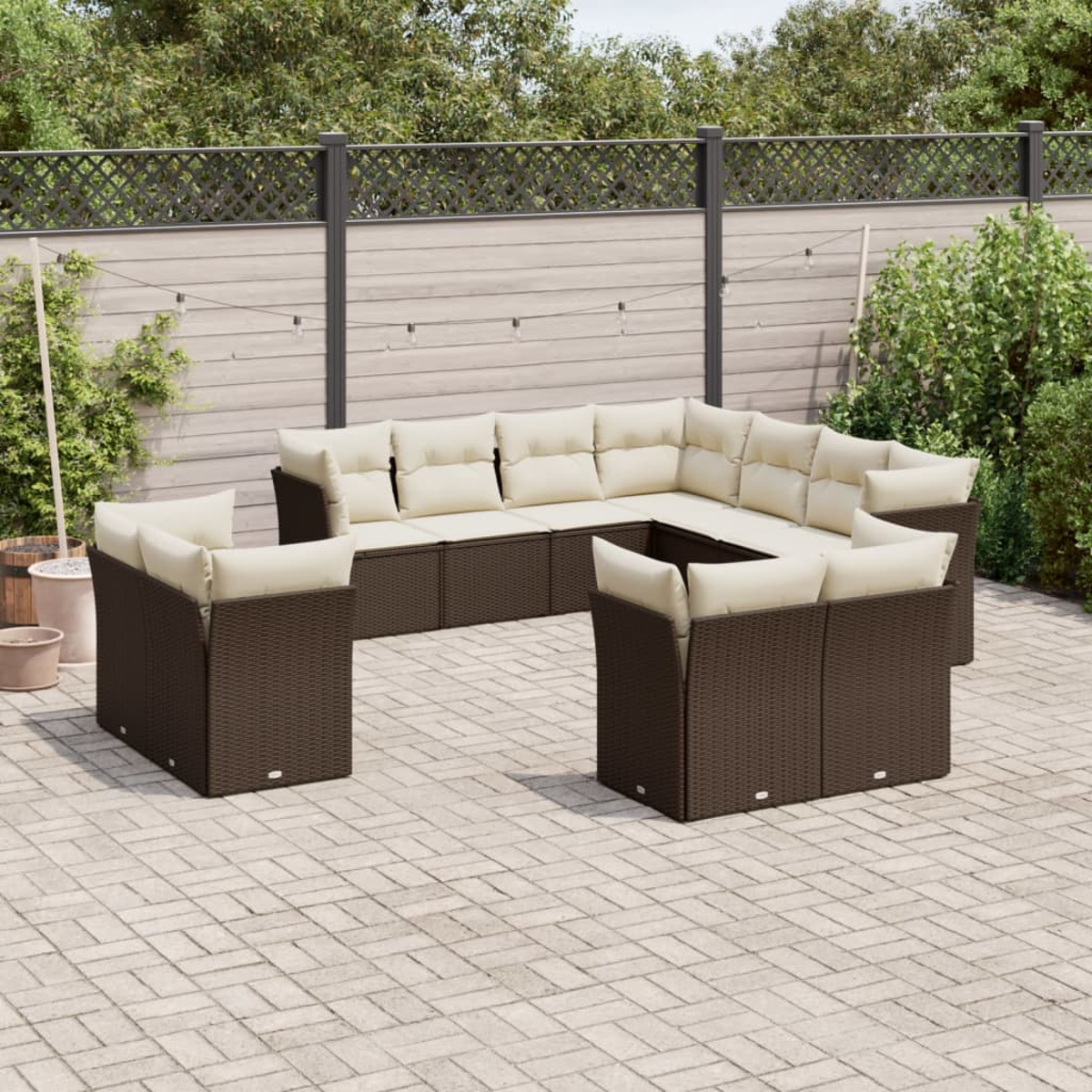 Dunkelbraunes Outdoor-Sofaset aus Korbgeflecht mit cremefarbenen Kissen auf Pflaster.
