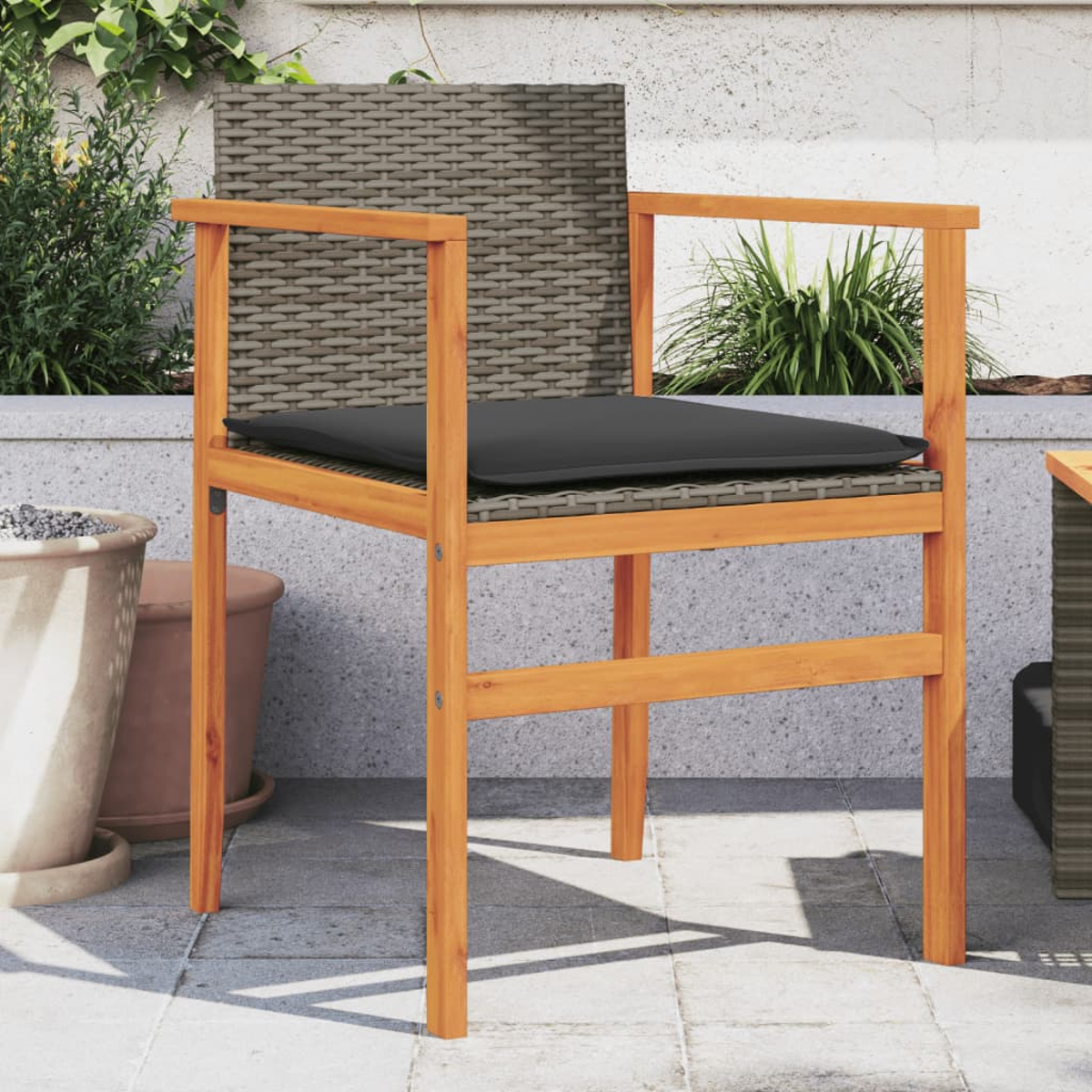 Holzstuhl mit gewebter Sitzfläche und Rückenlehne sowie einem schwarzen Kissen. Outdoor-Terrassenumgebung.