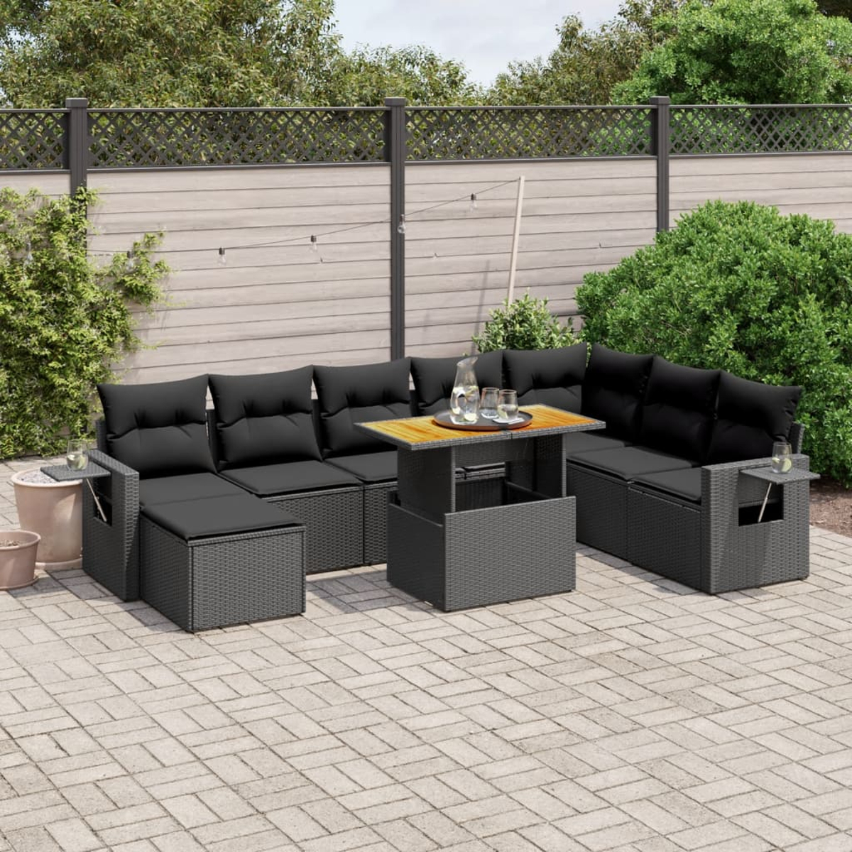 Gartenmöbel-Set mit schwarzen Kissen. Enthält ein Ecksofa, einen Couchtisch und Beistelltische. Ziegel-Terrasse.