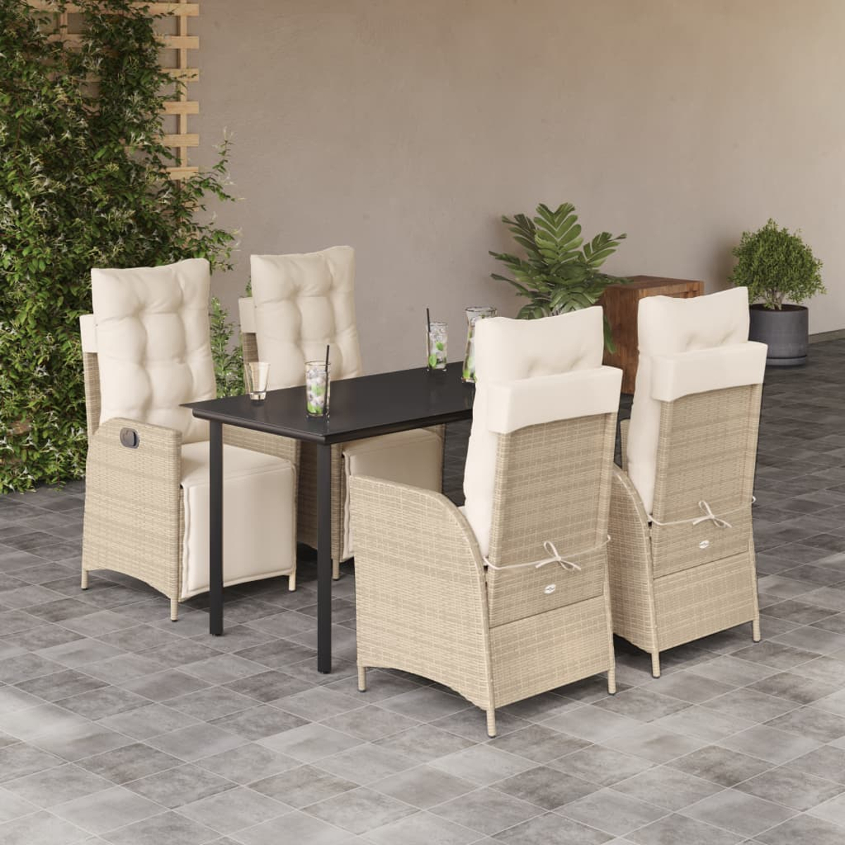 Set da pranzo all'aperto con tavolo e quattro sedie. Cuscini beige, tavolo nero, piante sullo sfondo.