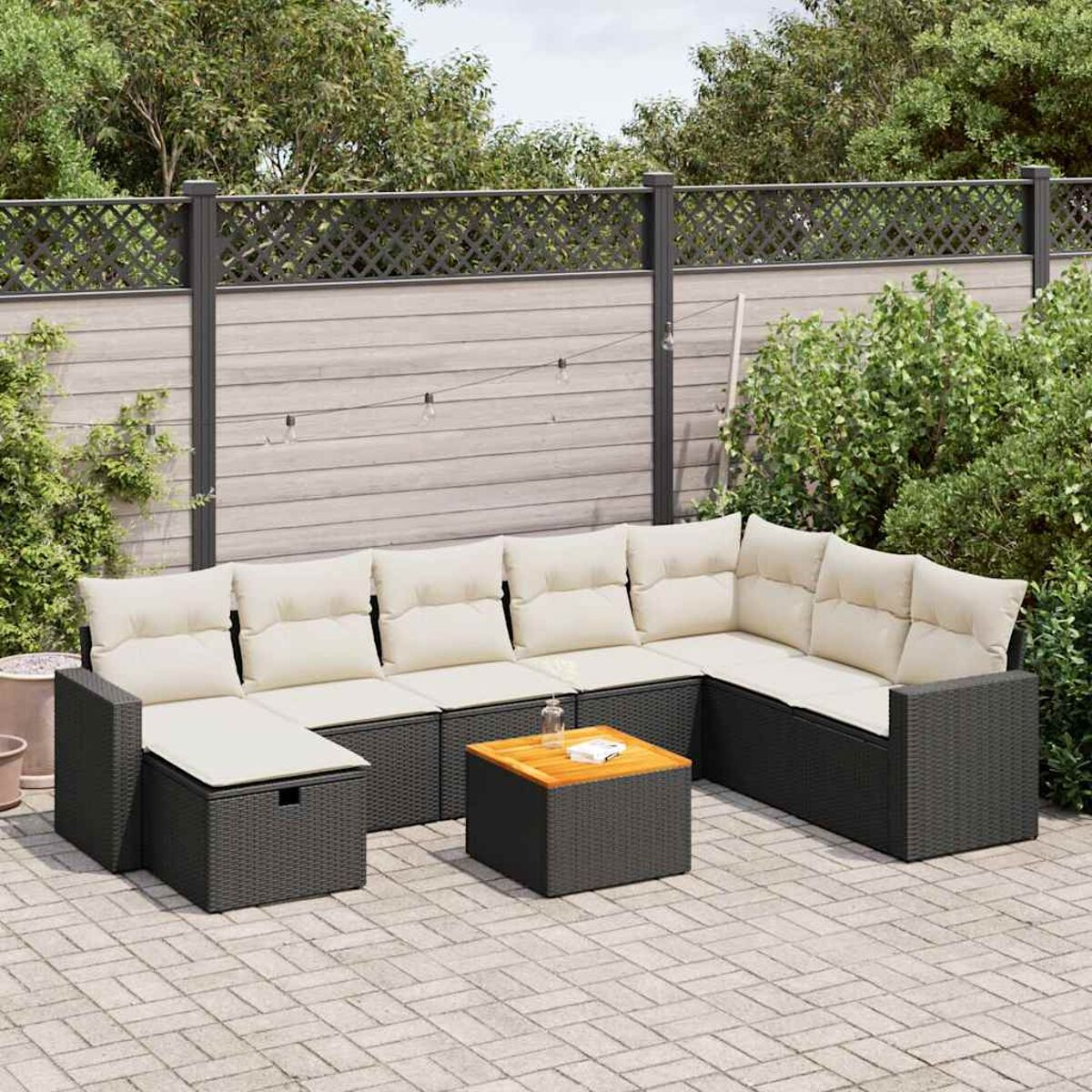 Outdoor-Ecksofa mit cremefarbenen Kissen und Holztisch auf einer Backstein-Terrasse, umgeben von einem Zaun und Pflanzen.