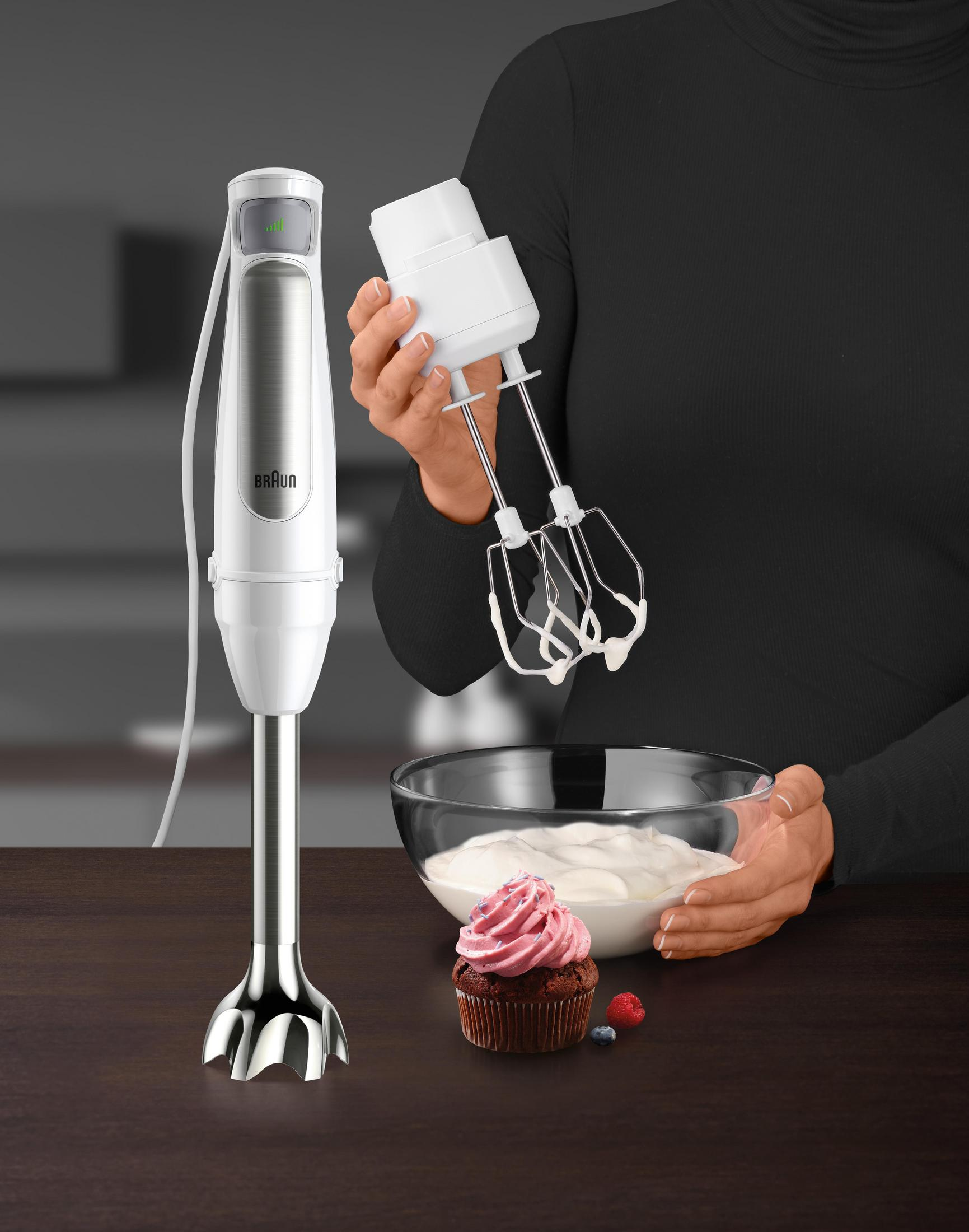 Blender ręczny i akcesoria. Kobieta trzyma końcówkę do ubijania. Babeczka i jagody.