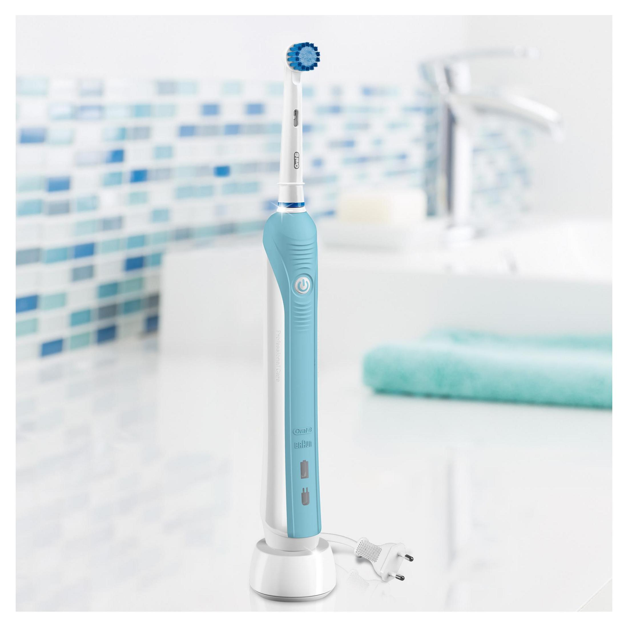 Un cepillo de dientes eléctrico azul y blanco con base de carga sobre superficie blanca en baño.