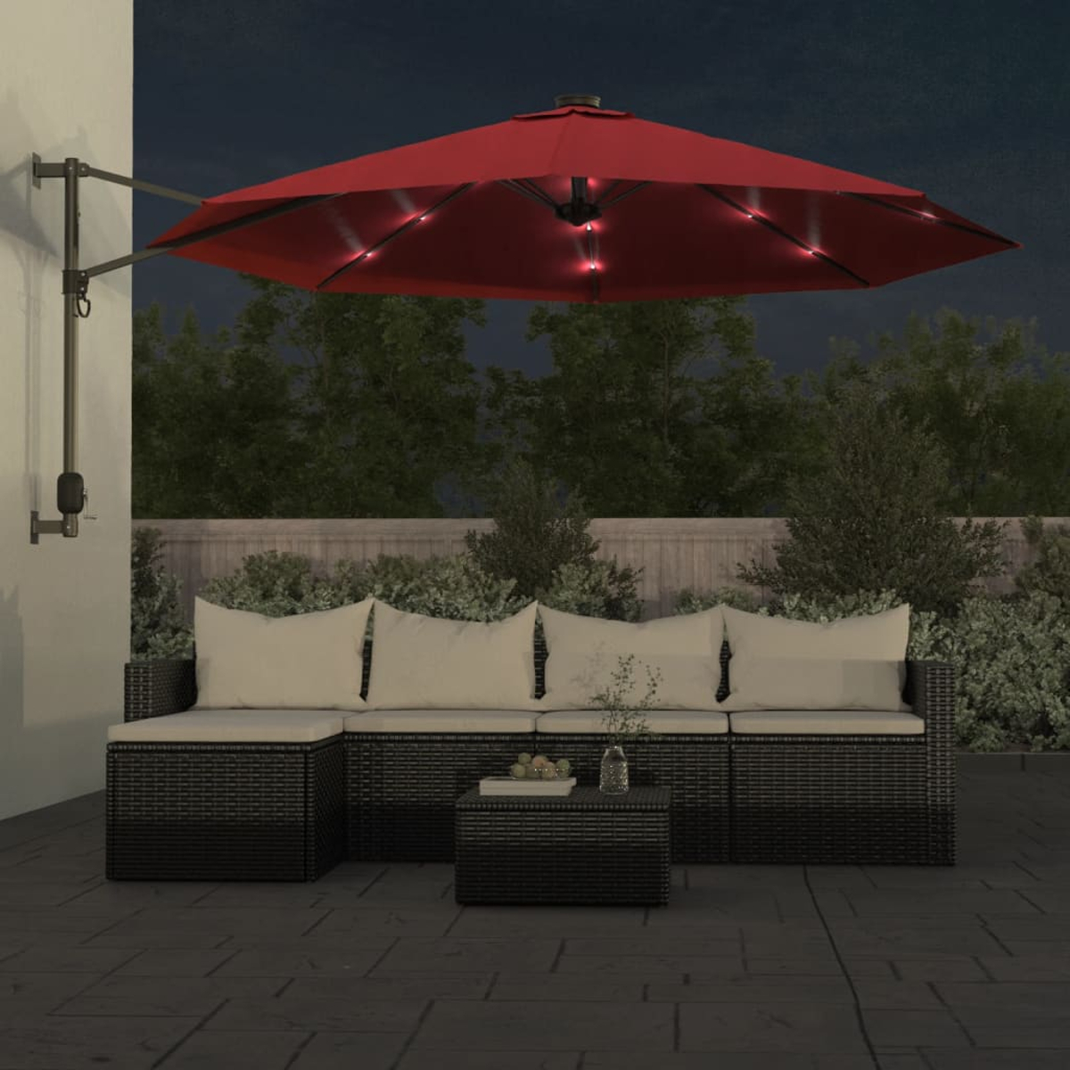 Outdoor-Setting mit rotem Schirm mit Lichtern, schwarzem Sofa und kleinem Holztisch.