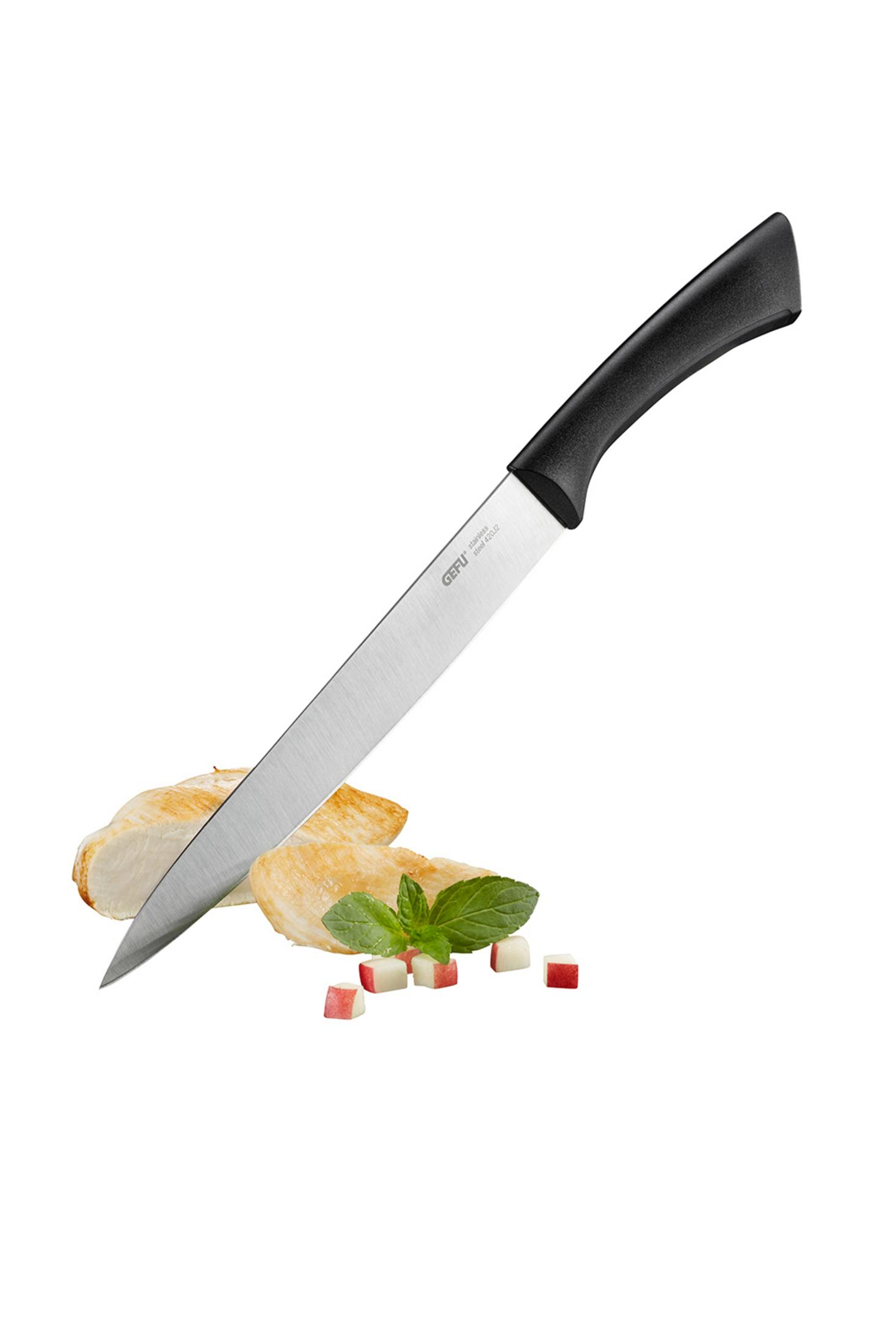 Küchenmesser schneidet Hähnchenbrust auf Holzbrett, mit Kräutern und Tomaten.