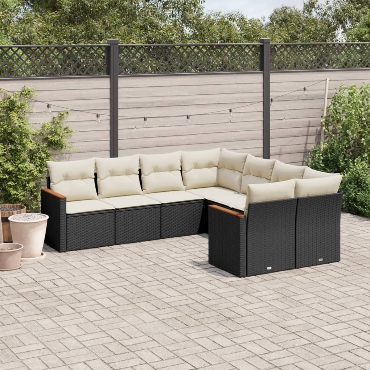 L-förmige Outdoor-Sofagarnitur in Schwarz, mit cremefarbenen Kissen, auf einer Terrasse.
