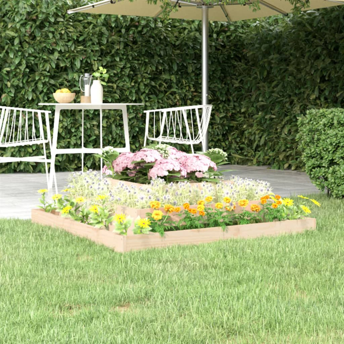 Erhöhtes Blumenbeet mit bunten Blumen, weißem Tisch und Sonnenschirm auf Rasen.