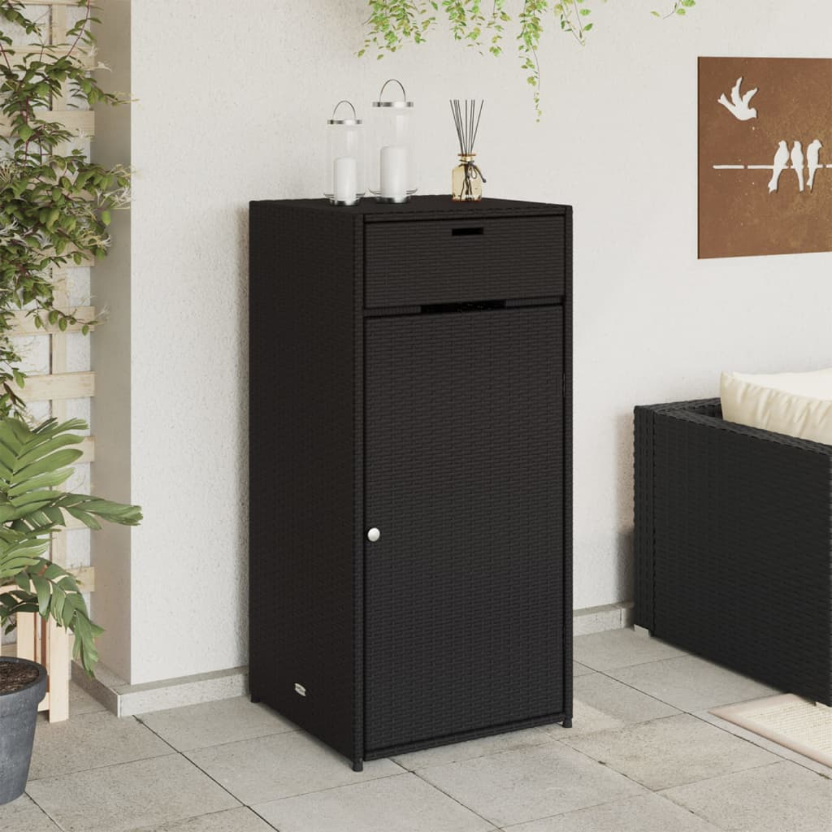 Schwarzer Outdoor-Aufbewahrungsschrank mit Tür und Schublade. Auf Pflasterterrasse.